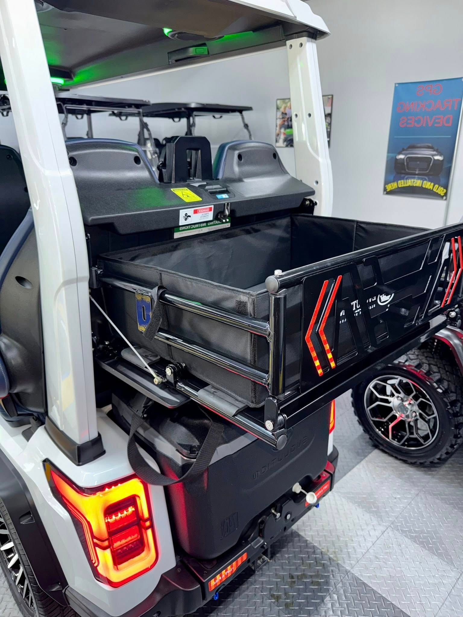 A golf cart with a tray in the back is parked in a garage.