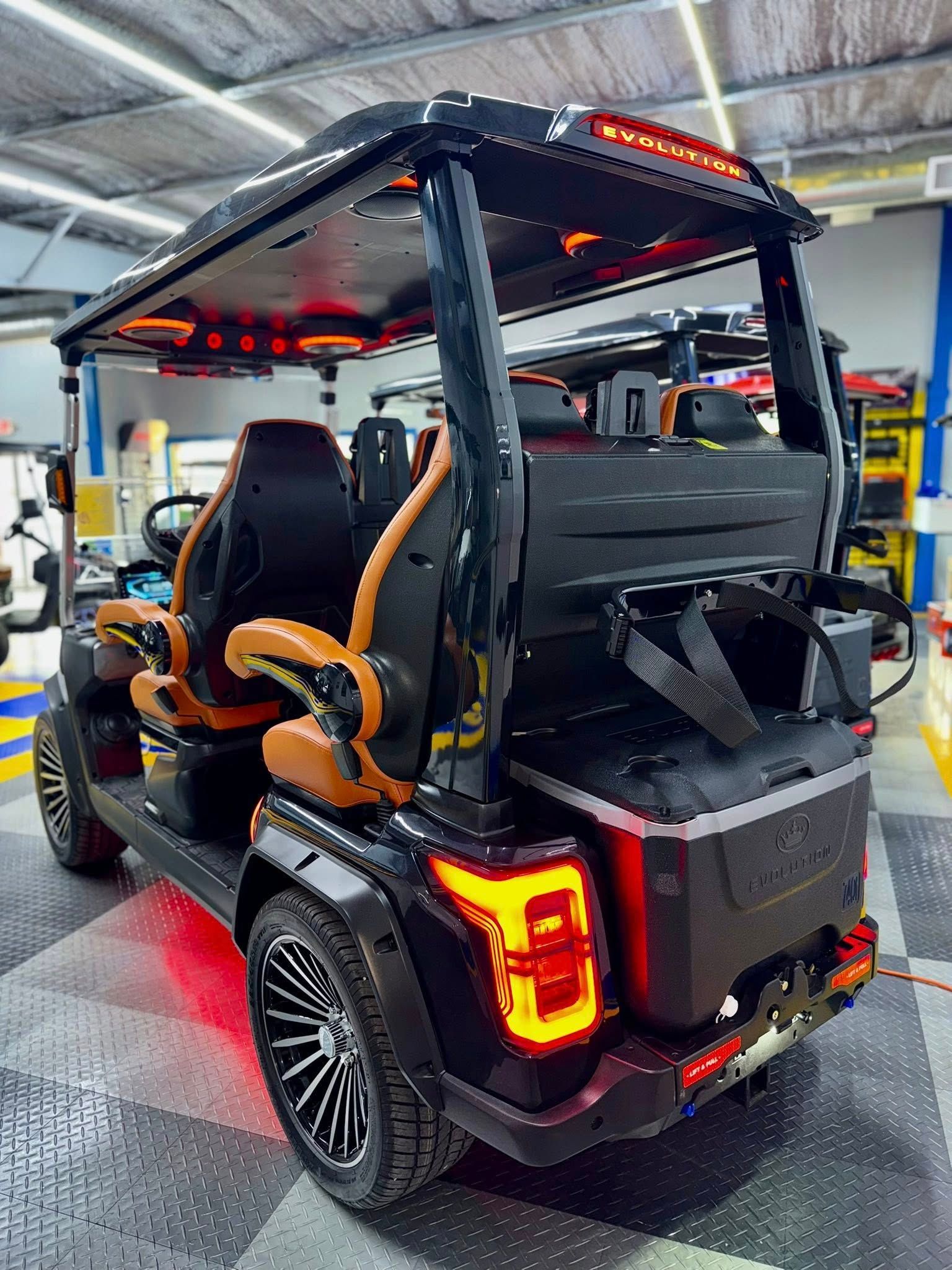 Black and brown custom golf cart with LED lighting and stylish seats, in a garage setting.