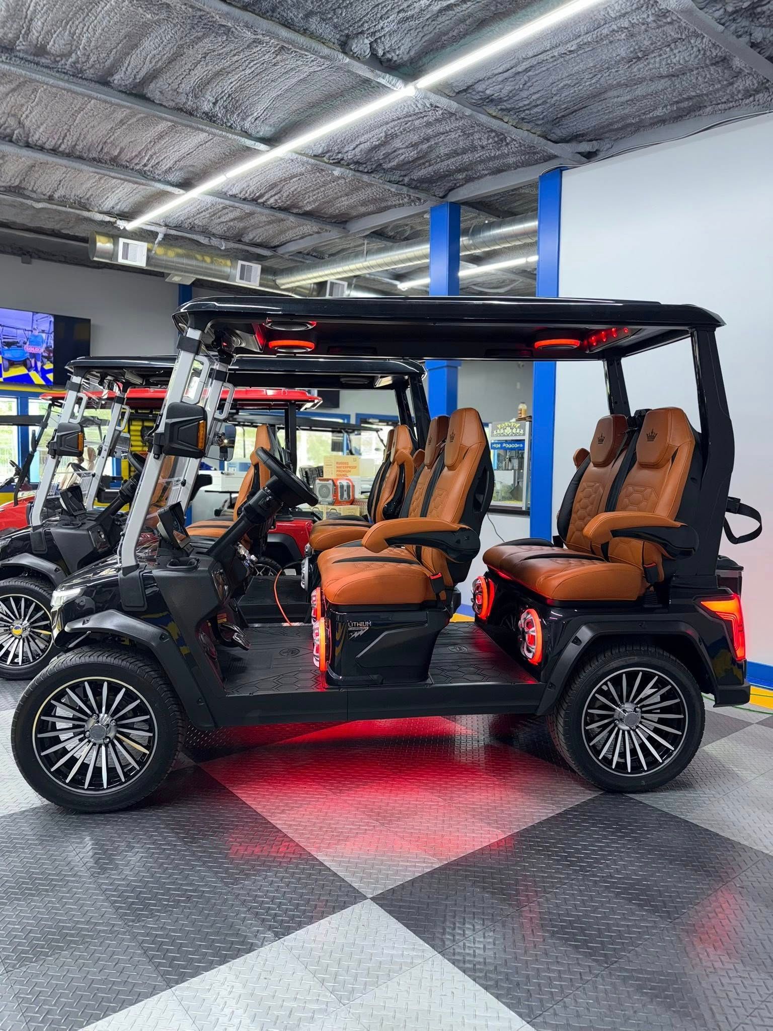 Black golf cart with brown leather seats, custom wheels, and underglow in a showroom.