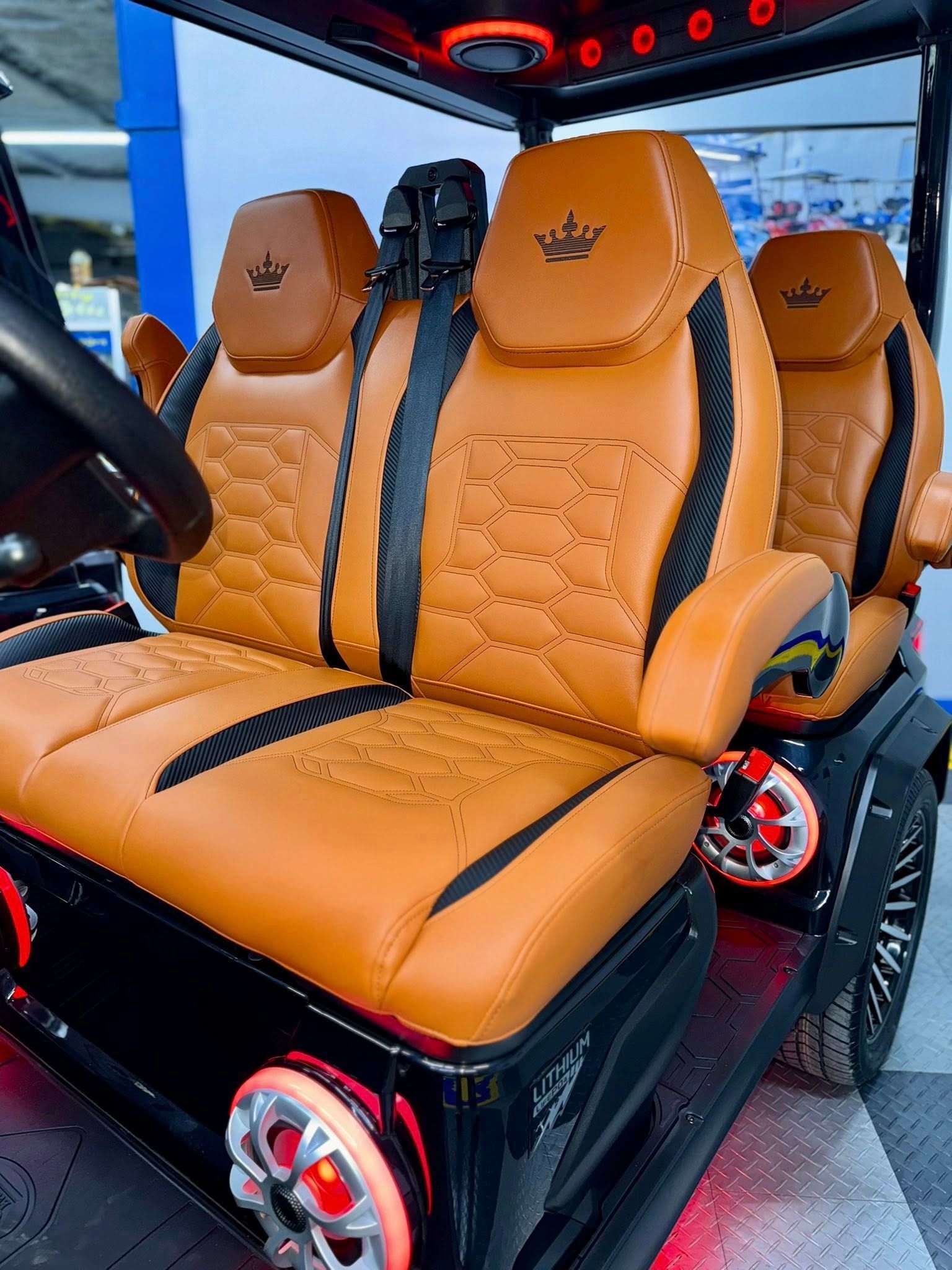 Tan and black golf cart interior, seats with diamond stitching, black trim, red lighting.