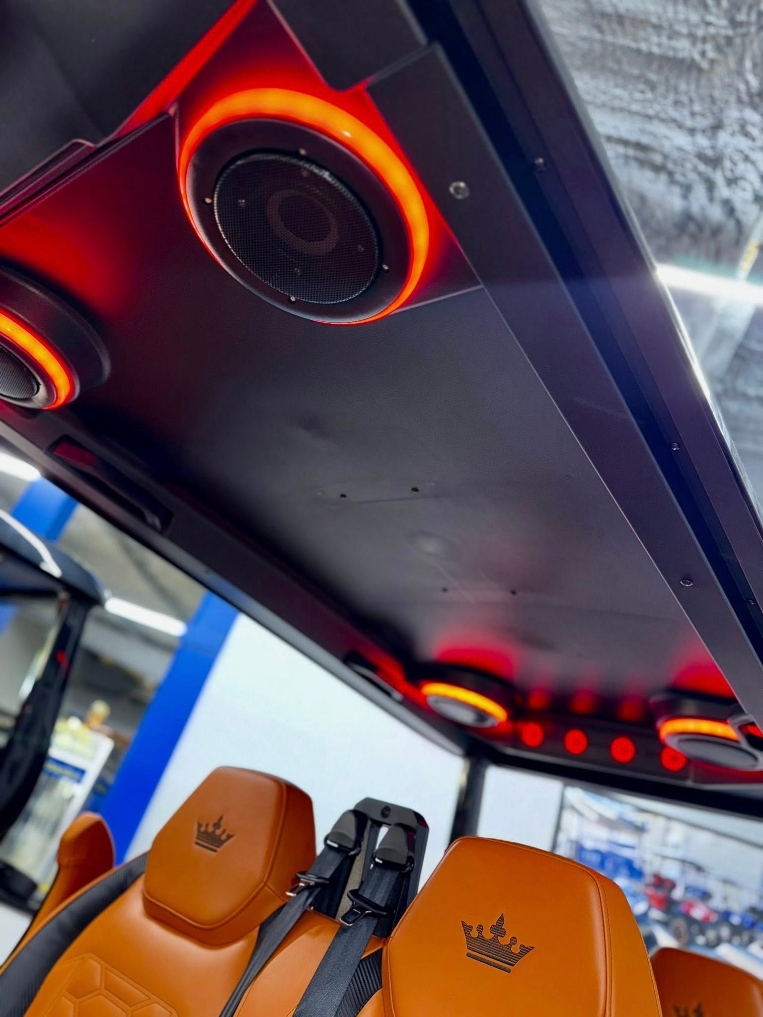 Golf cart interior with orange seats, speakers, and red lights.