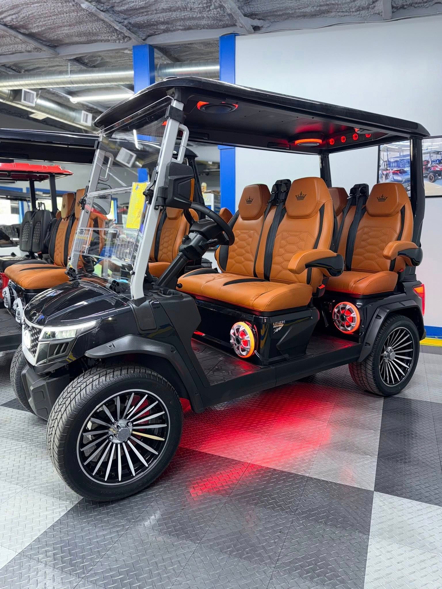 Black 8-passenger golf cart with brown leather seats, LED lights, and black and silver wheels on a checkered floor.