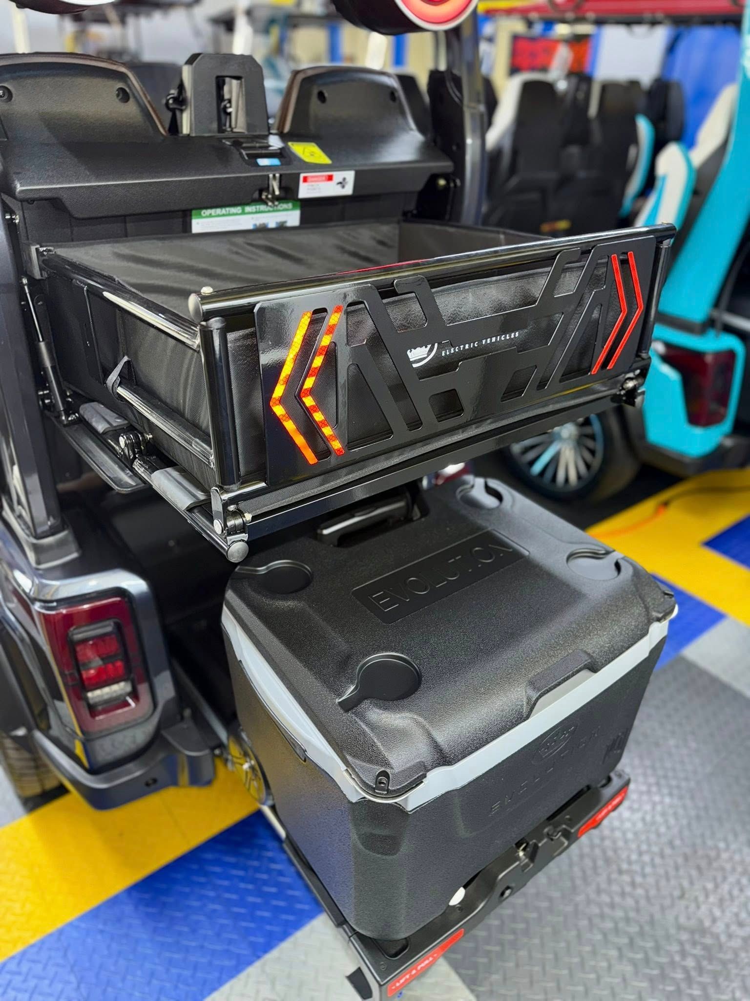 Black vehicle with a storage basket and cooler on the back, with yellow and blue flooring.