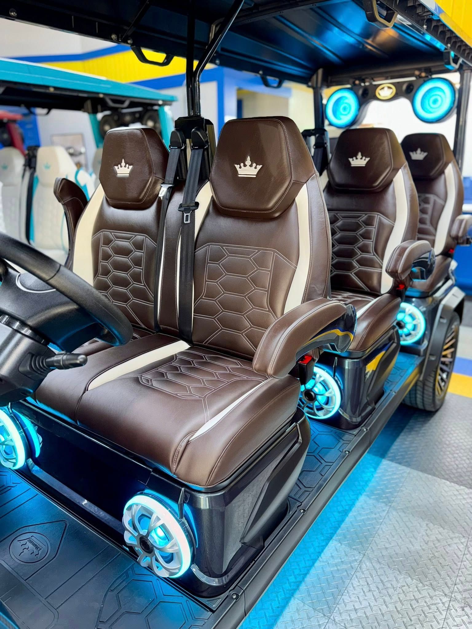 Brown and white golf cart with custom seats, lights, and a crown logo.
