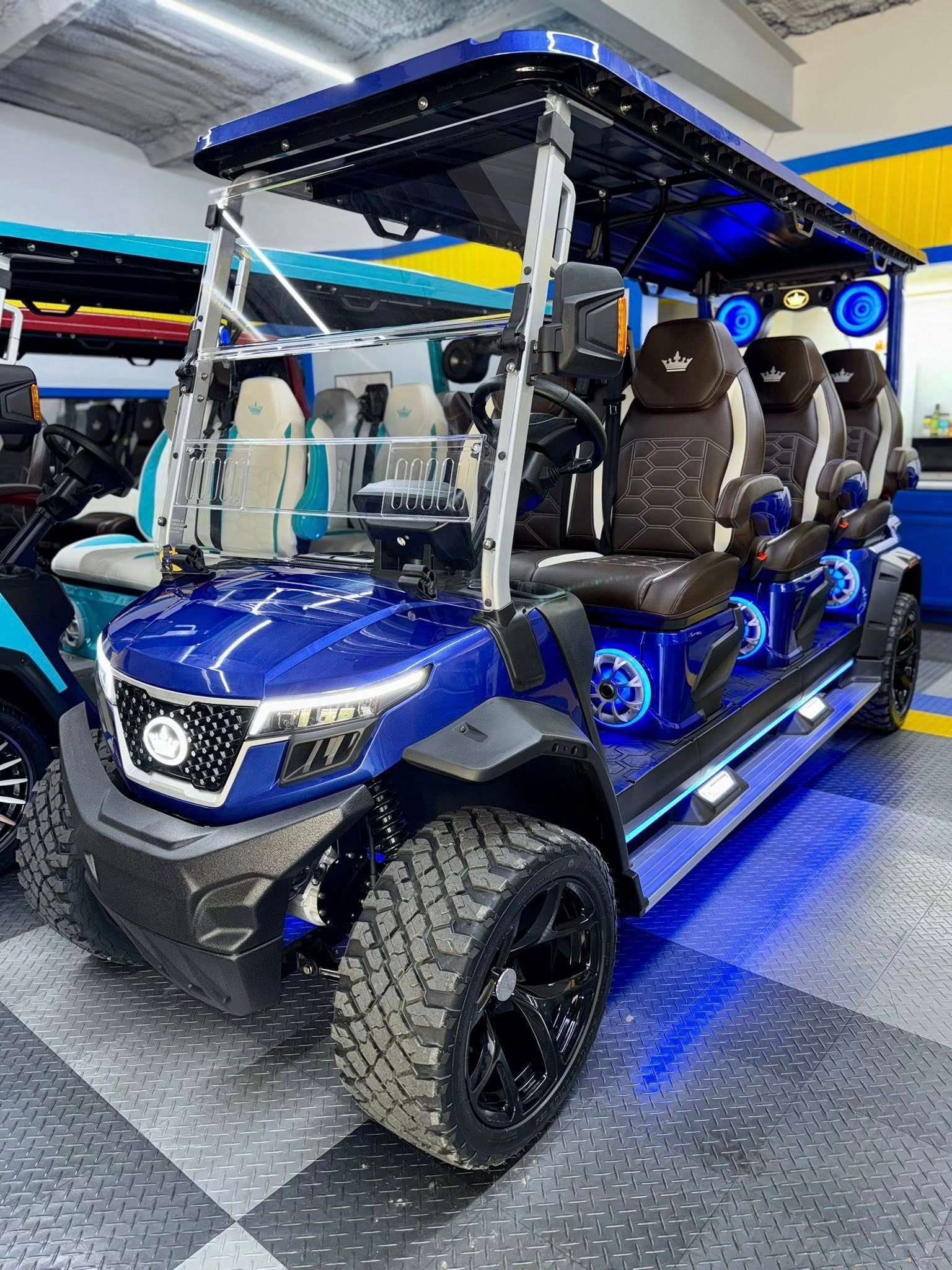 Blue and black luxury golf cart with off-road tires, LED lights, and custom seating.