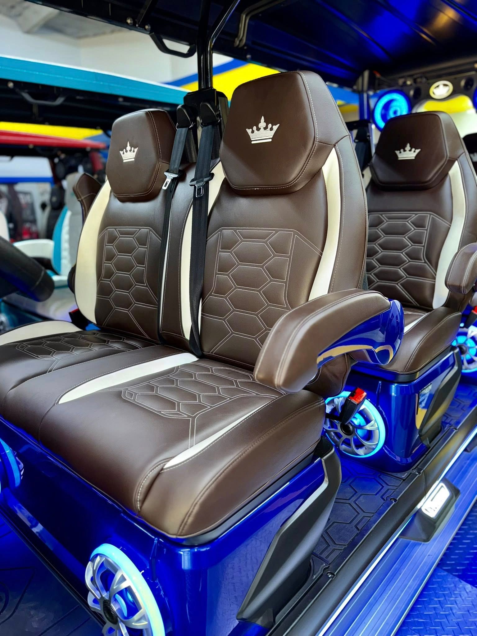 Brown and beige leather seats with crown logos in a blue golf cart interior.