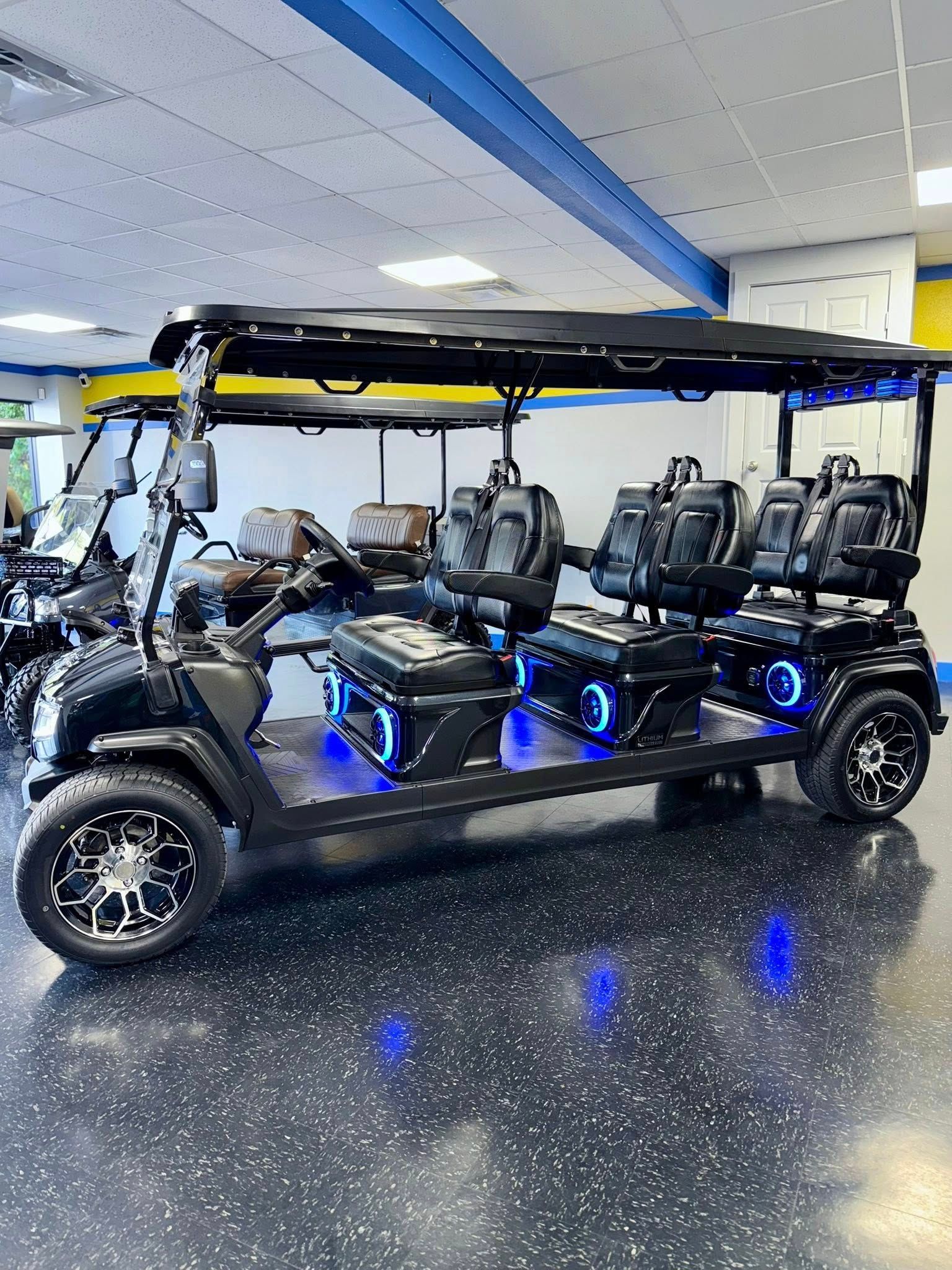 Black, six-passenger golf cart with blue underglow lights on display in a showroom.