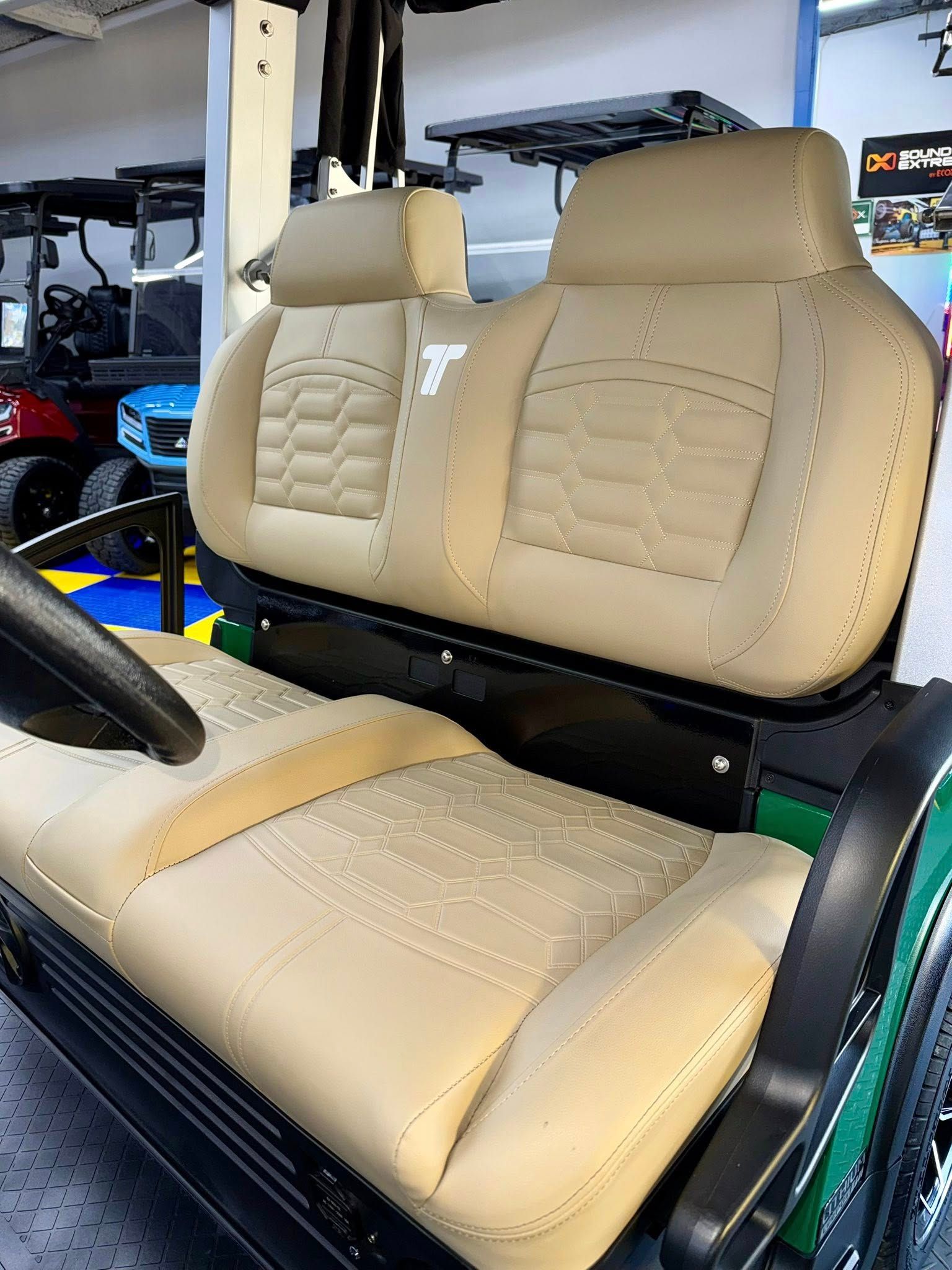 Beige golf cart seats with stitched detailing. Black trim and a green cart frame are visible.