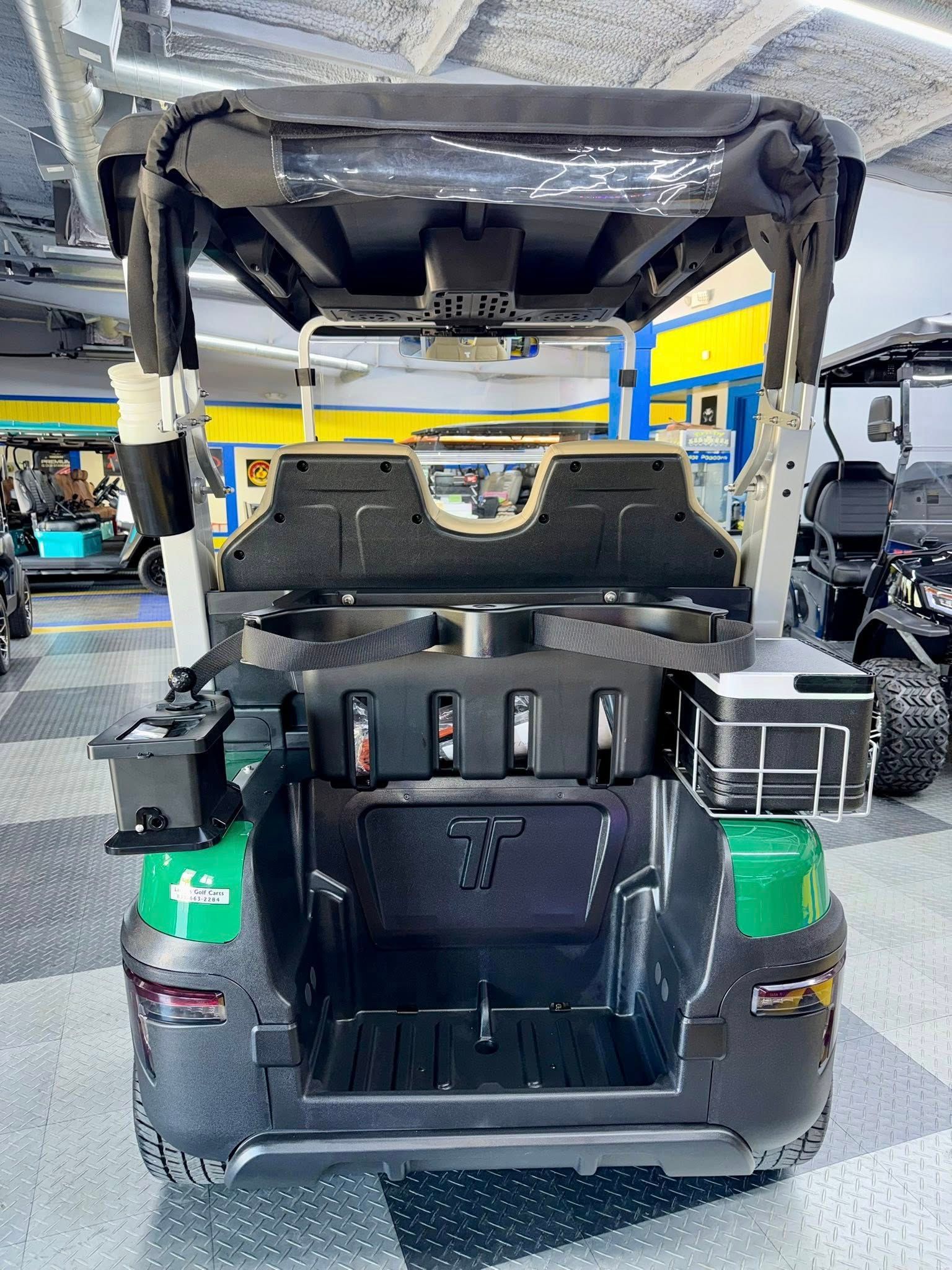 Rear view of a dark green and black golf cart with a storage area and roof.