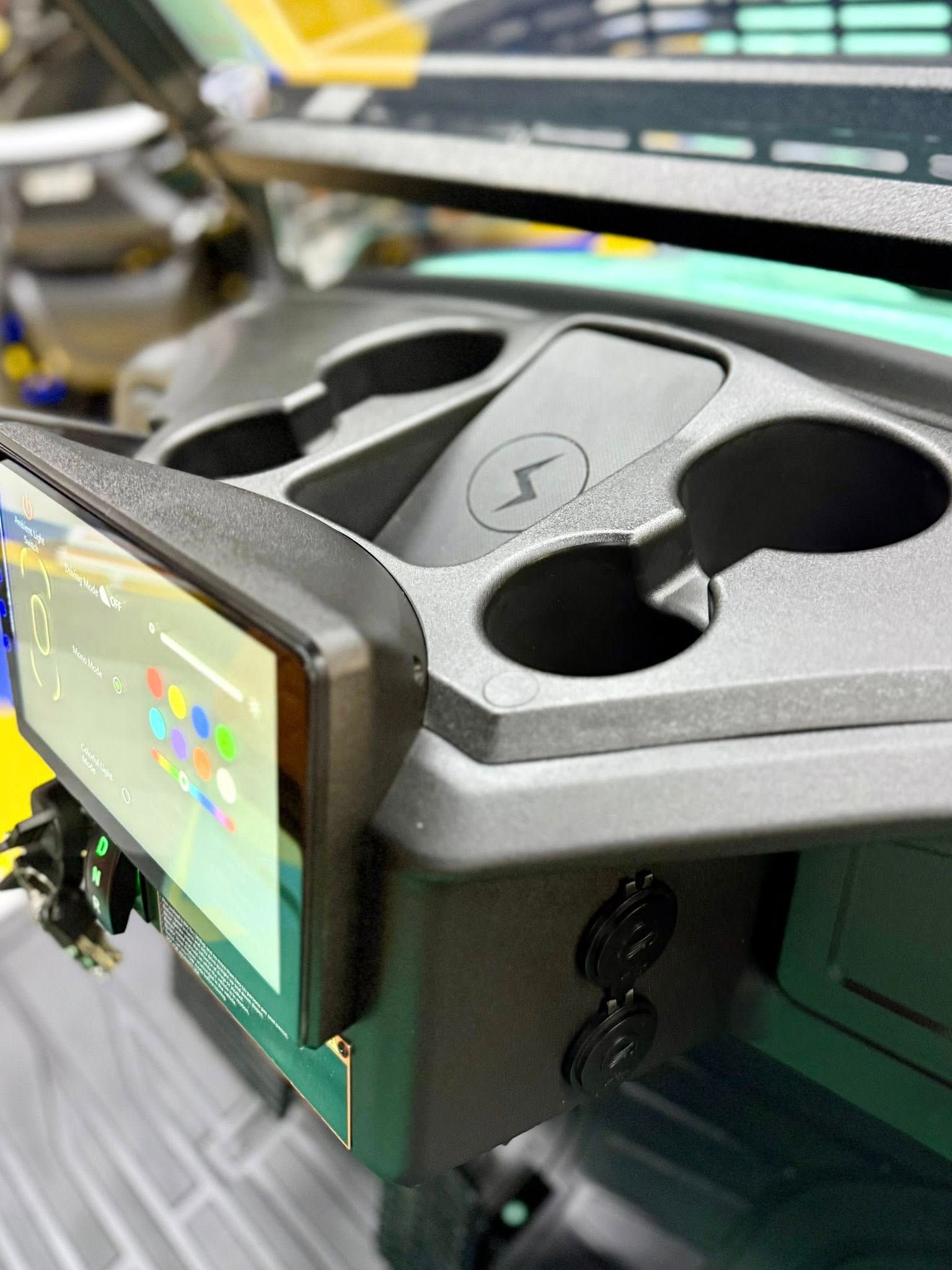 Black console with cupholders, wireless charger, and touchscreen display.