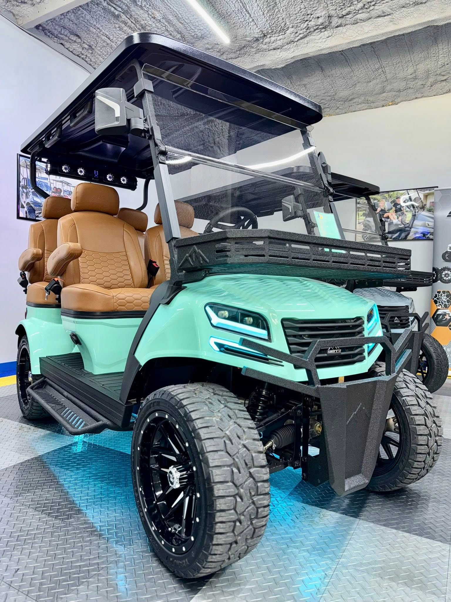 Mint green lifted golf cart with brown seats, black wheels, and roof in a showroom.