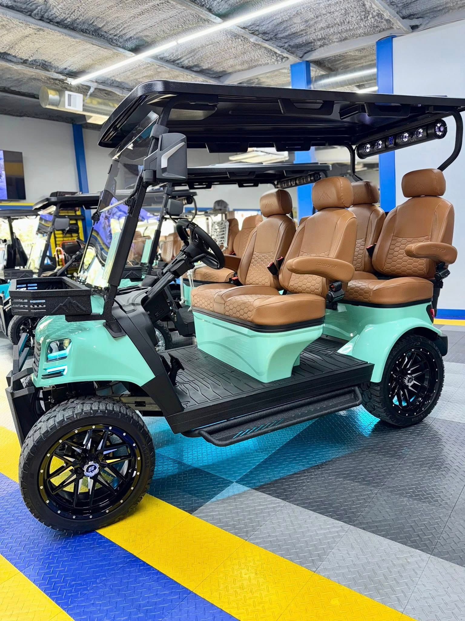 Mint-green golf cart with black trim, black wheels, brown seats, and a black roof.