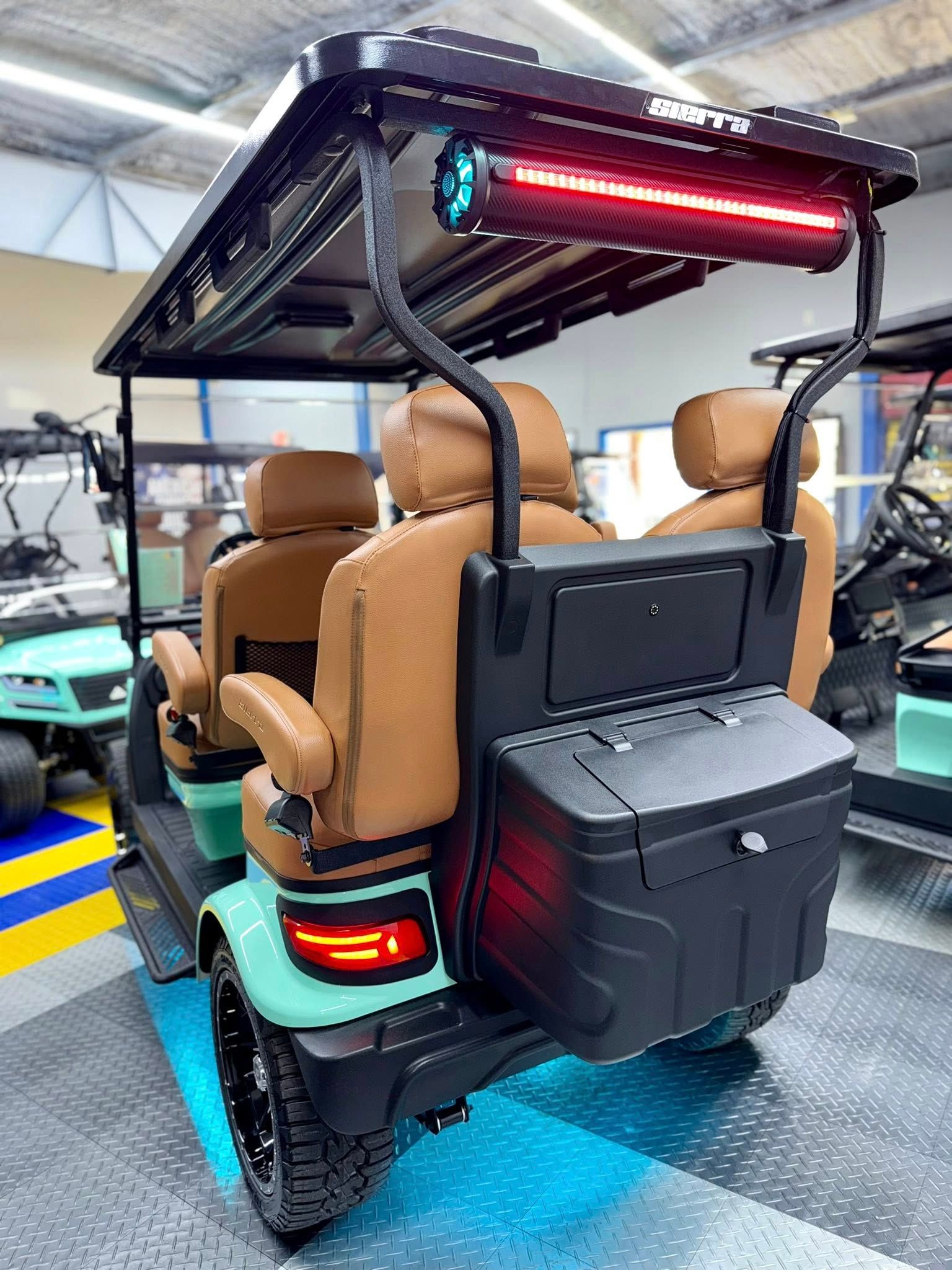 Mint green golf cart with brown seats, black roof, and a rear cooler.