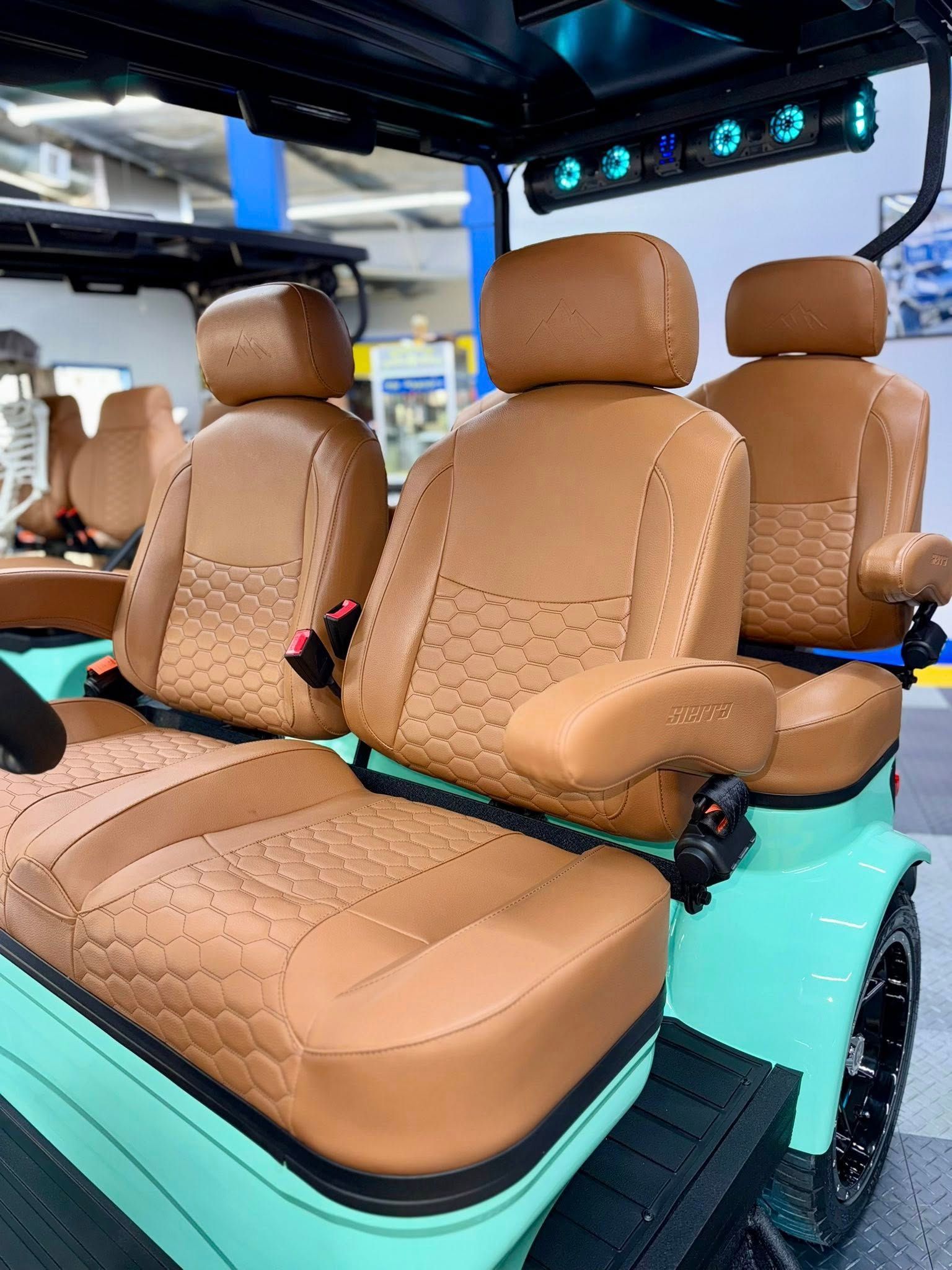 Mint green golf cart with tan leather seats, black tires, and overhead lighting.