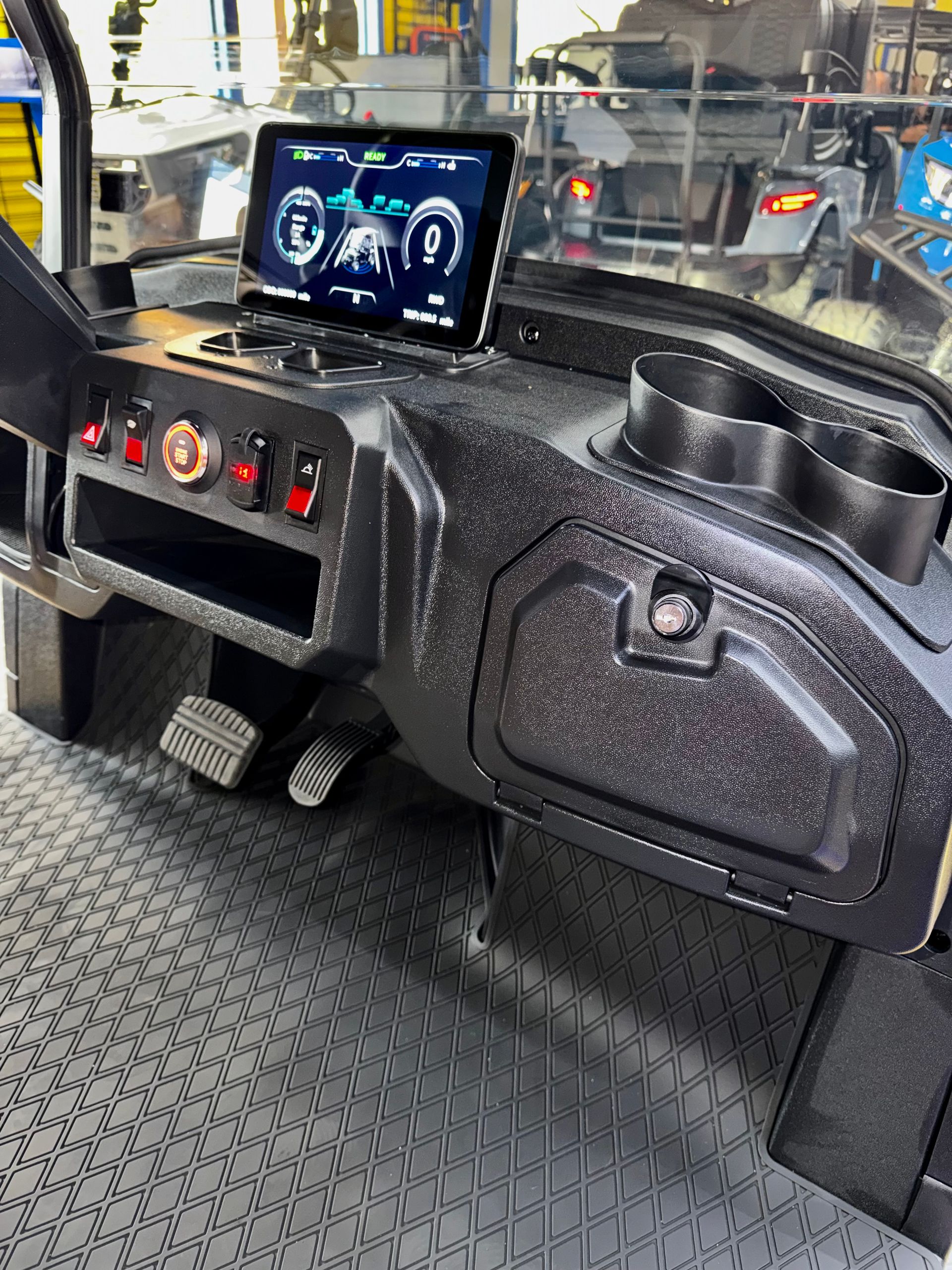 Golf cart dashboard with digital display, control switches, and cupholders inside a vehicle