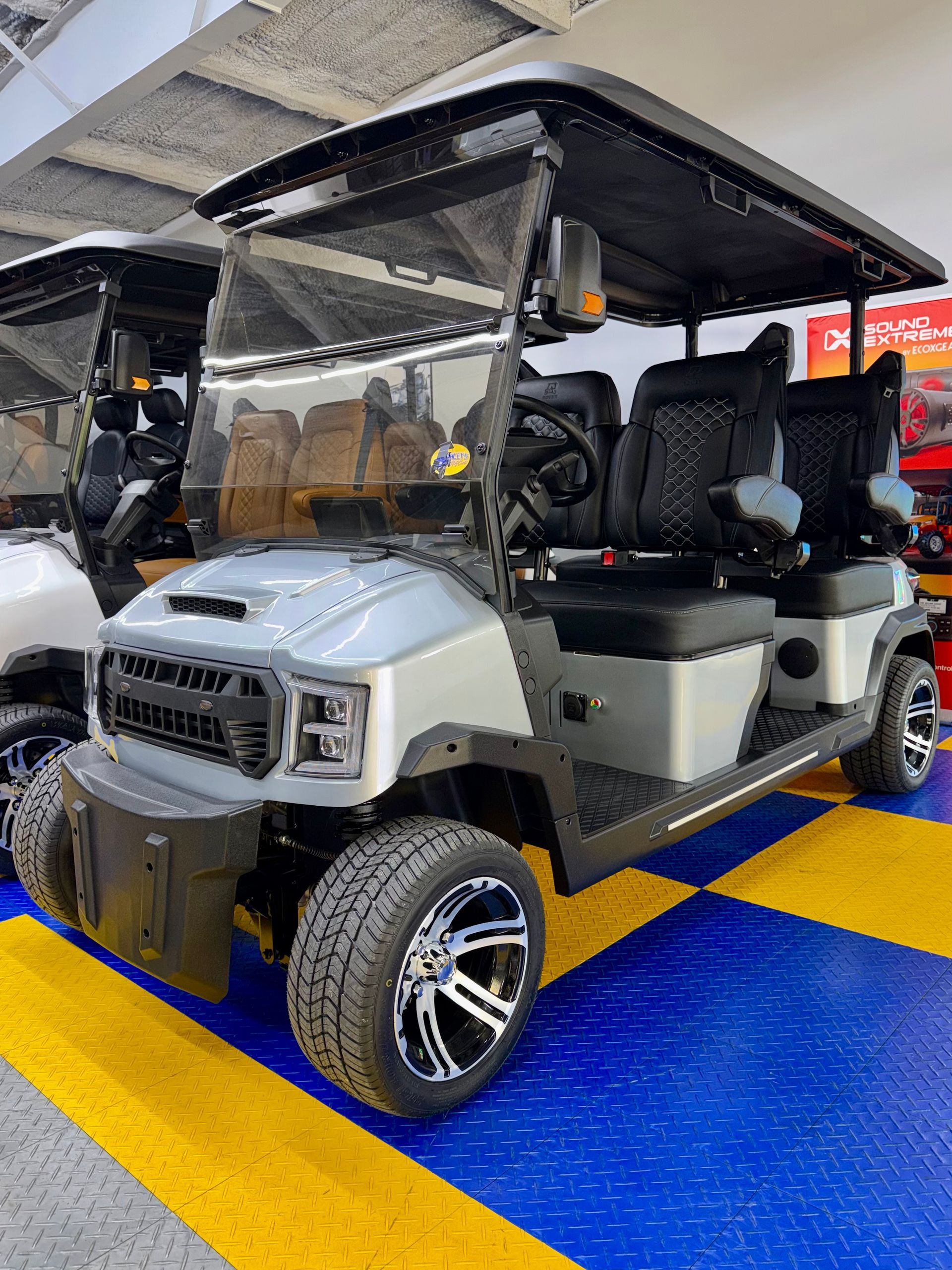 White golf cart with black roof parked indoors on a blue-and-yellow floor.
