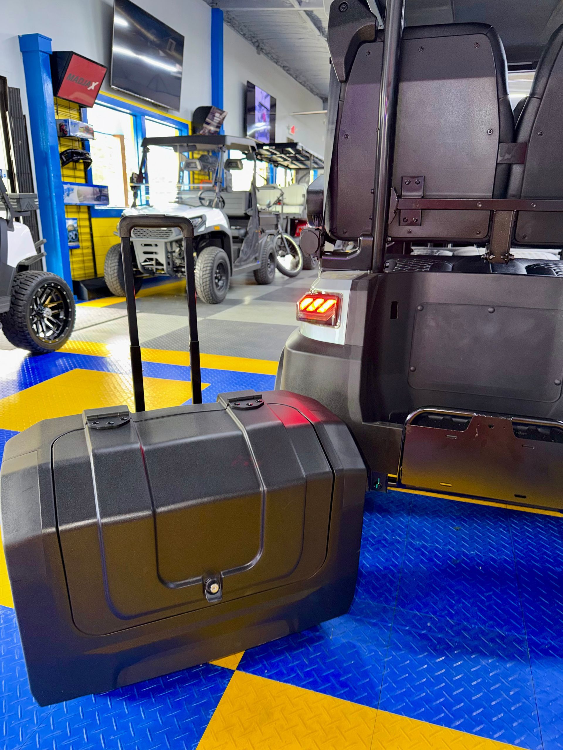 Black suitcase on a blue-and-yellow airport baggage cart in a terminal walkway