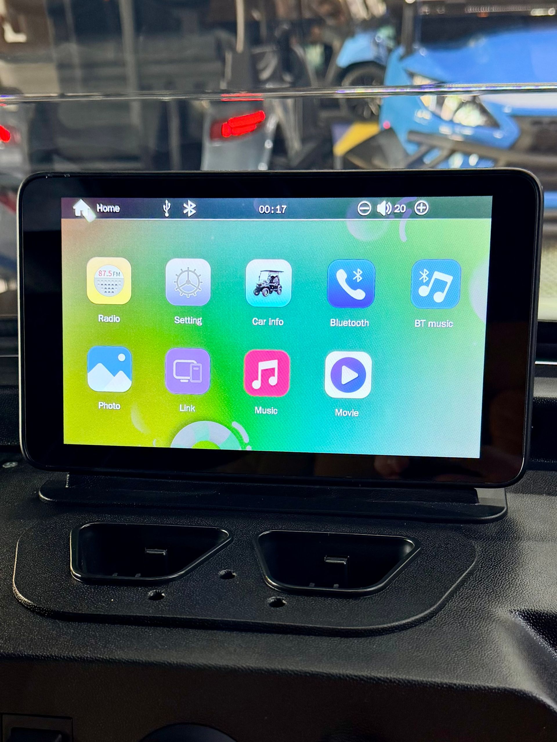 Car dashboard touchscreen showing a colorful home screen with app icons and a media player interface