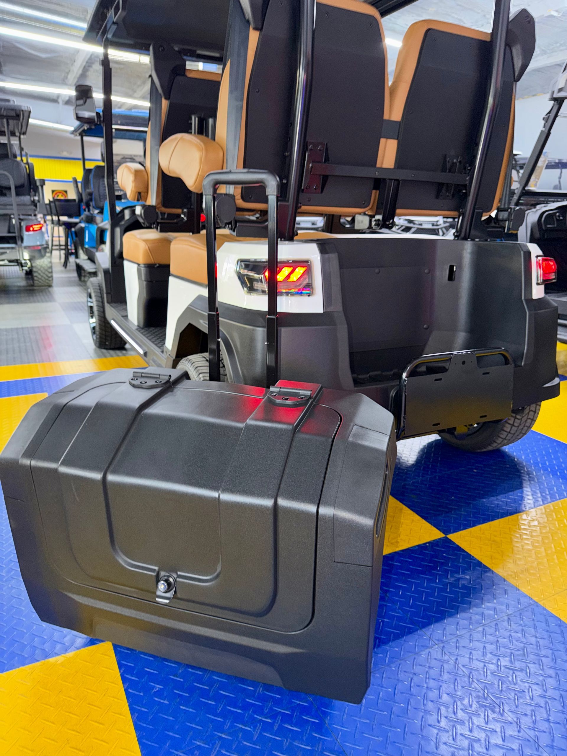 Black mobility scooter with large rear cargo box indoors on a blue-and-yellow floor