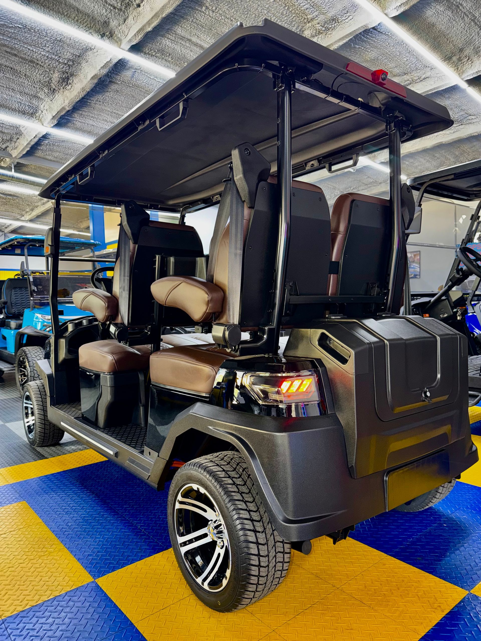 Black golf cart with tan seats parked indoors on a blue-and-yellow checkered floor.