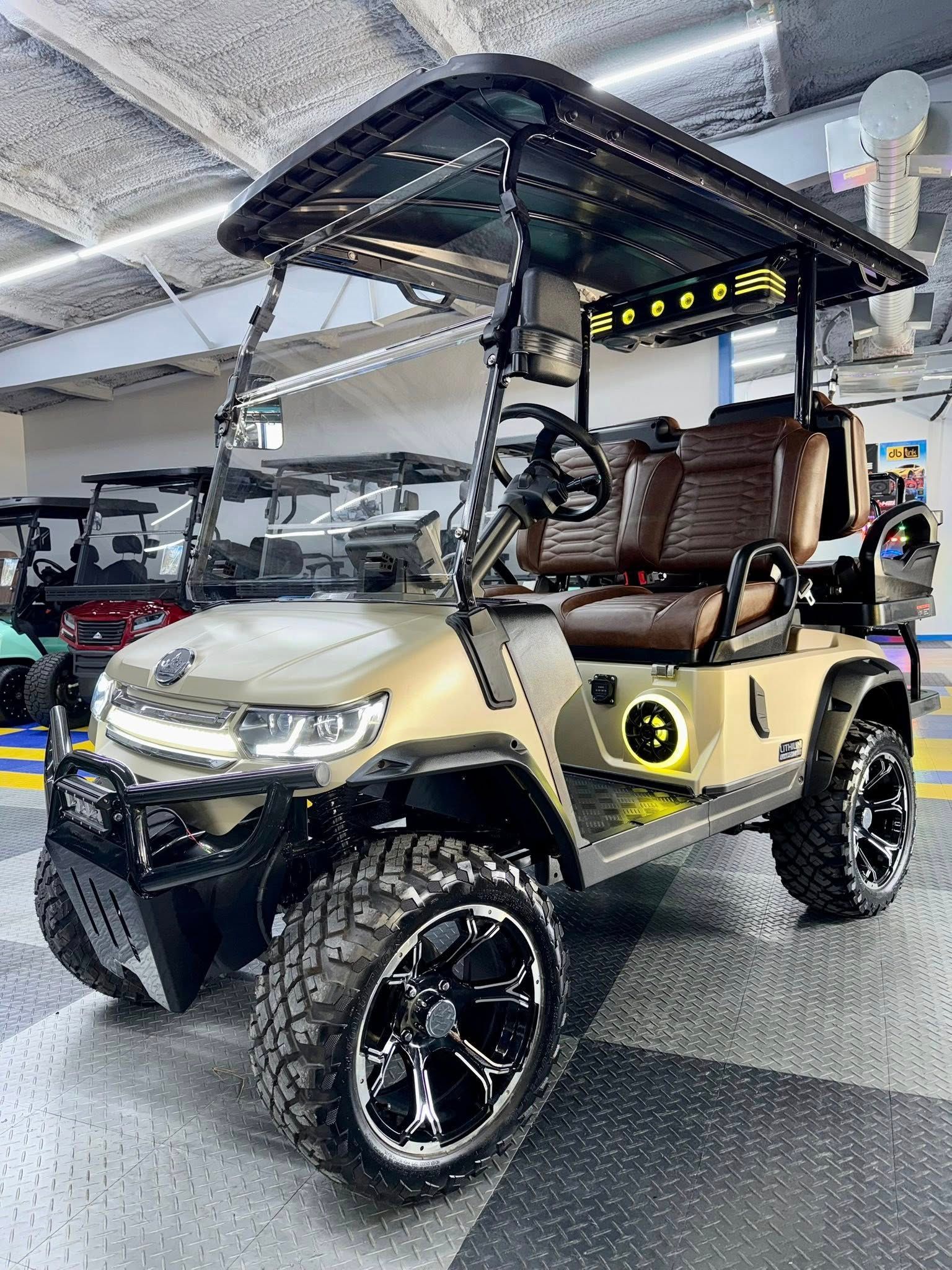 Tan and black customized golf cart with large wheels, under garage lighting.