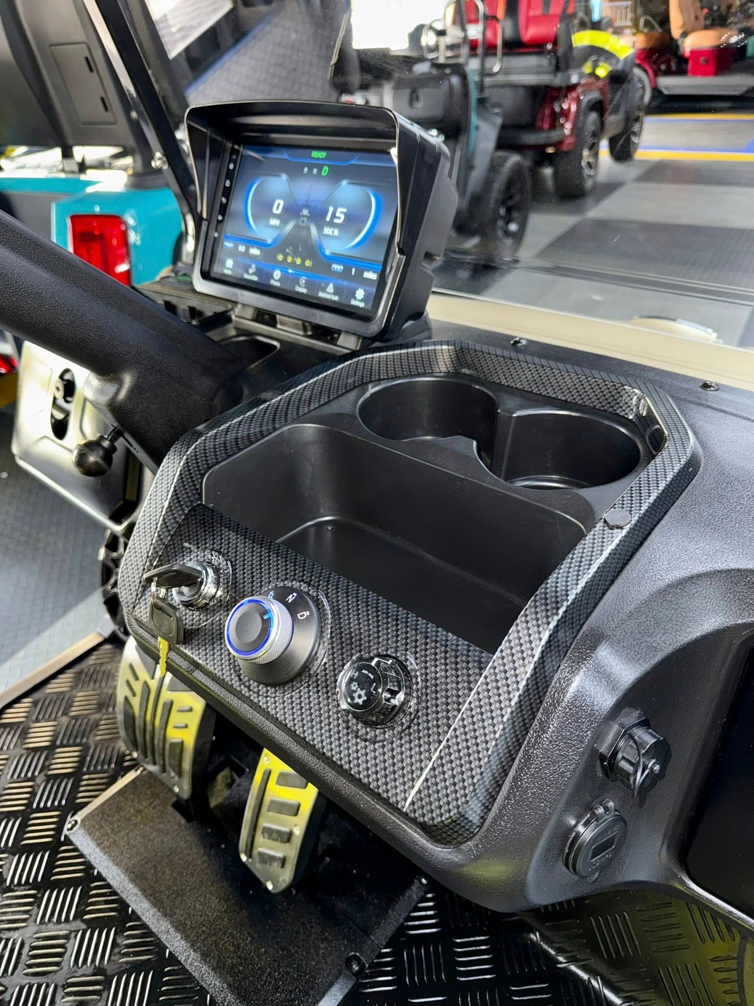 Golf cart dashboard with a digital display, cup holders, and carbon fiber accents.