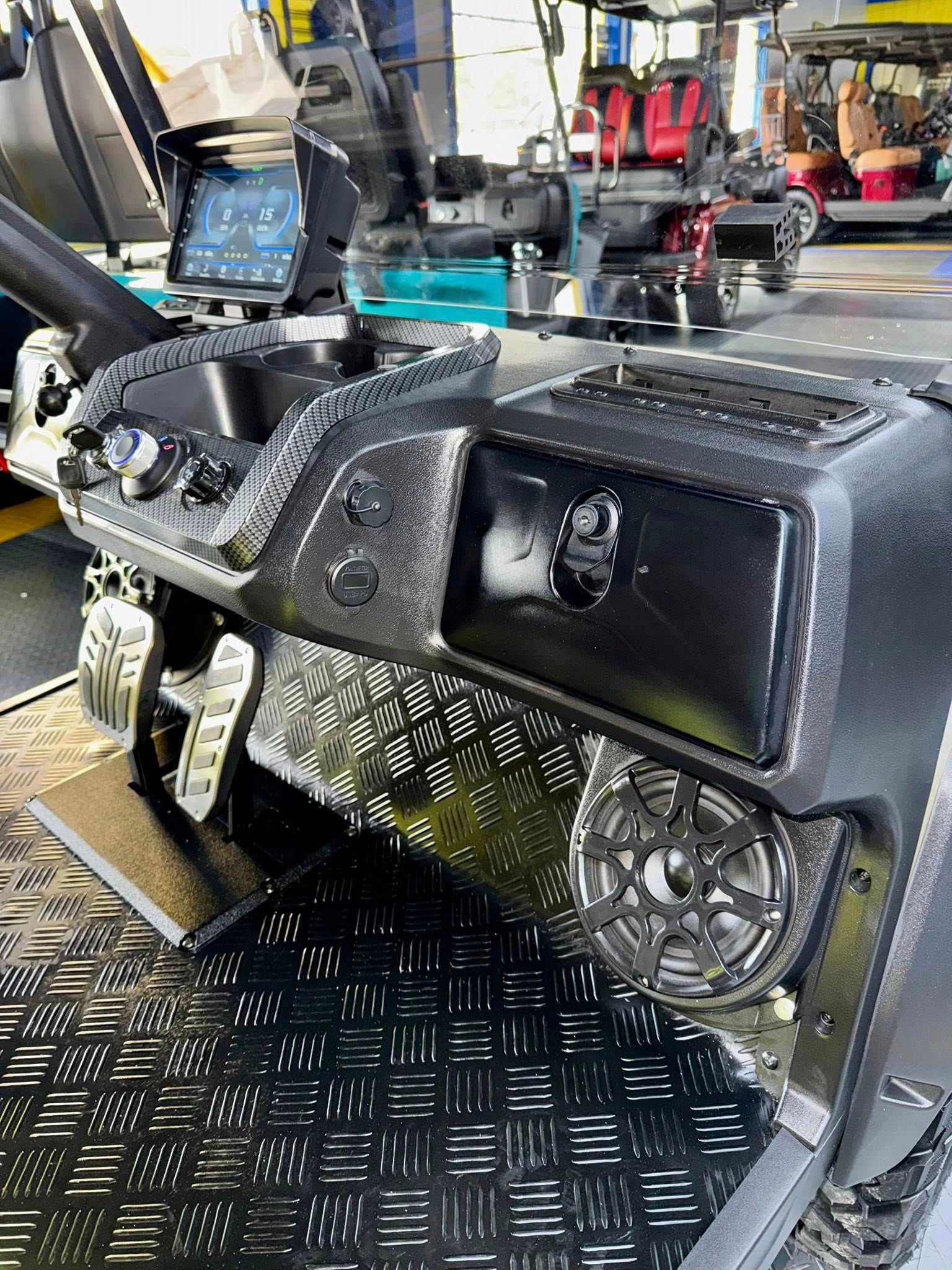 Dashboard of a utility vehicle with diamond plate floor and speaker. Black and gray.