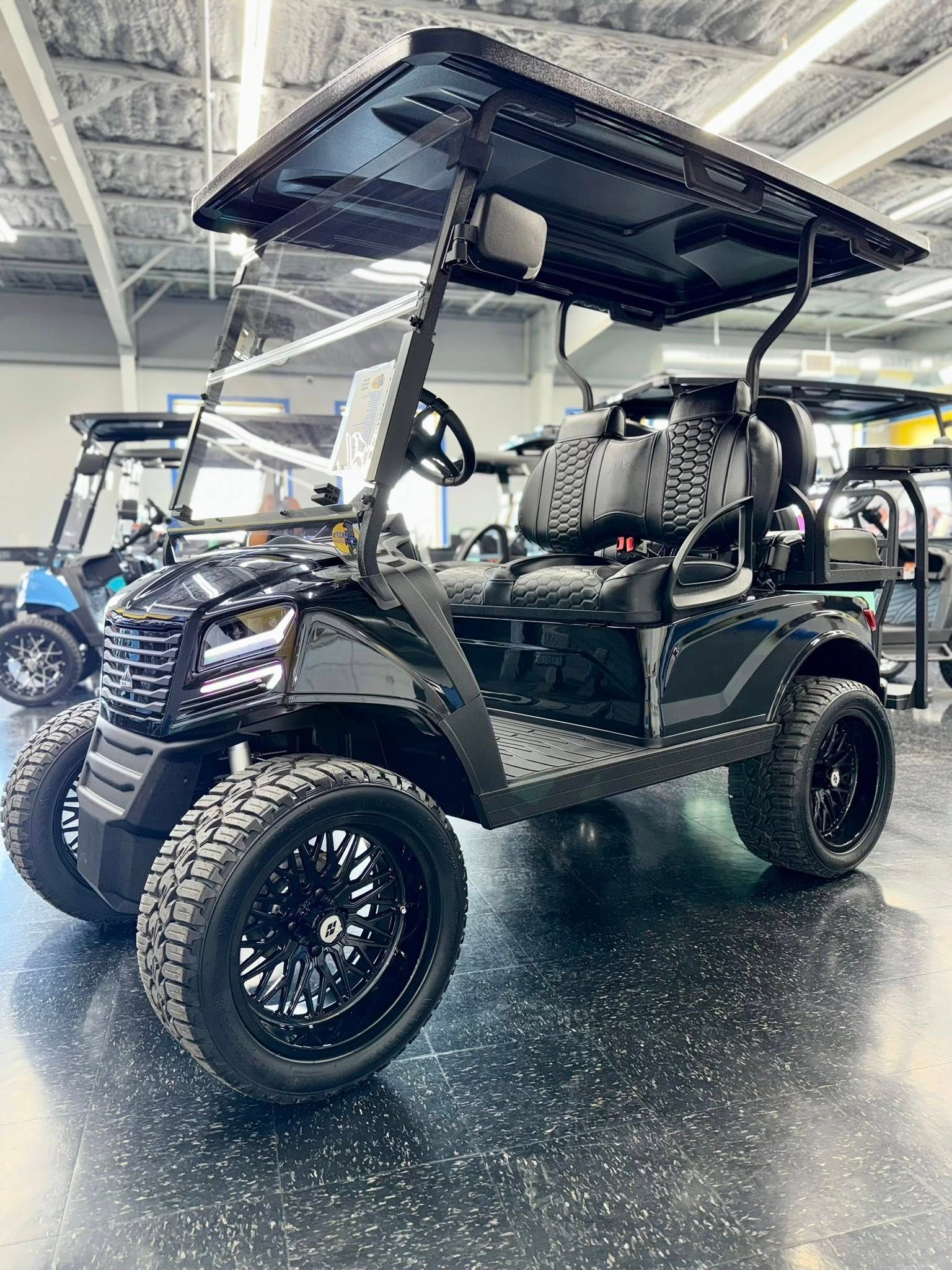 Black golf cart with large tires, in a showroom.