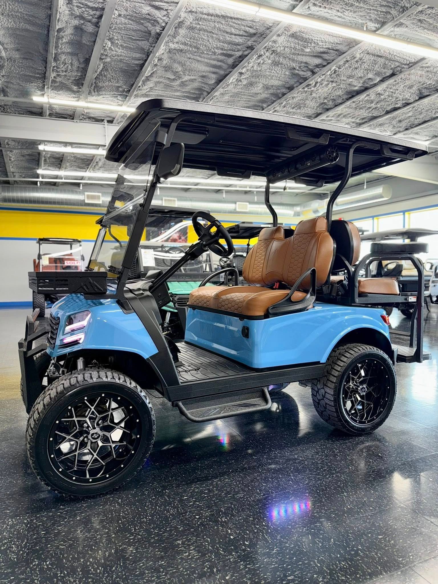 Blue golf cart with black roof and wheels, brown seats, in a showroom.