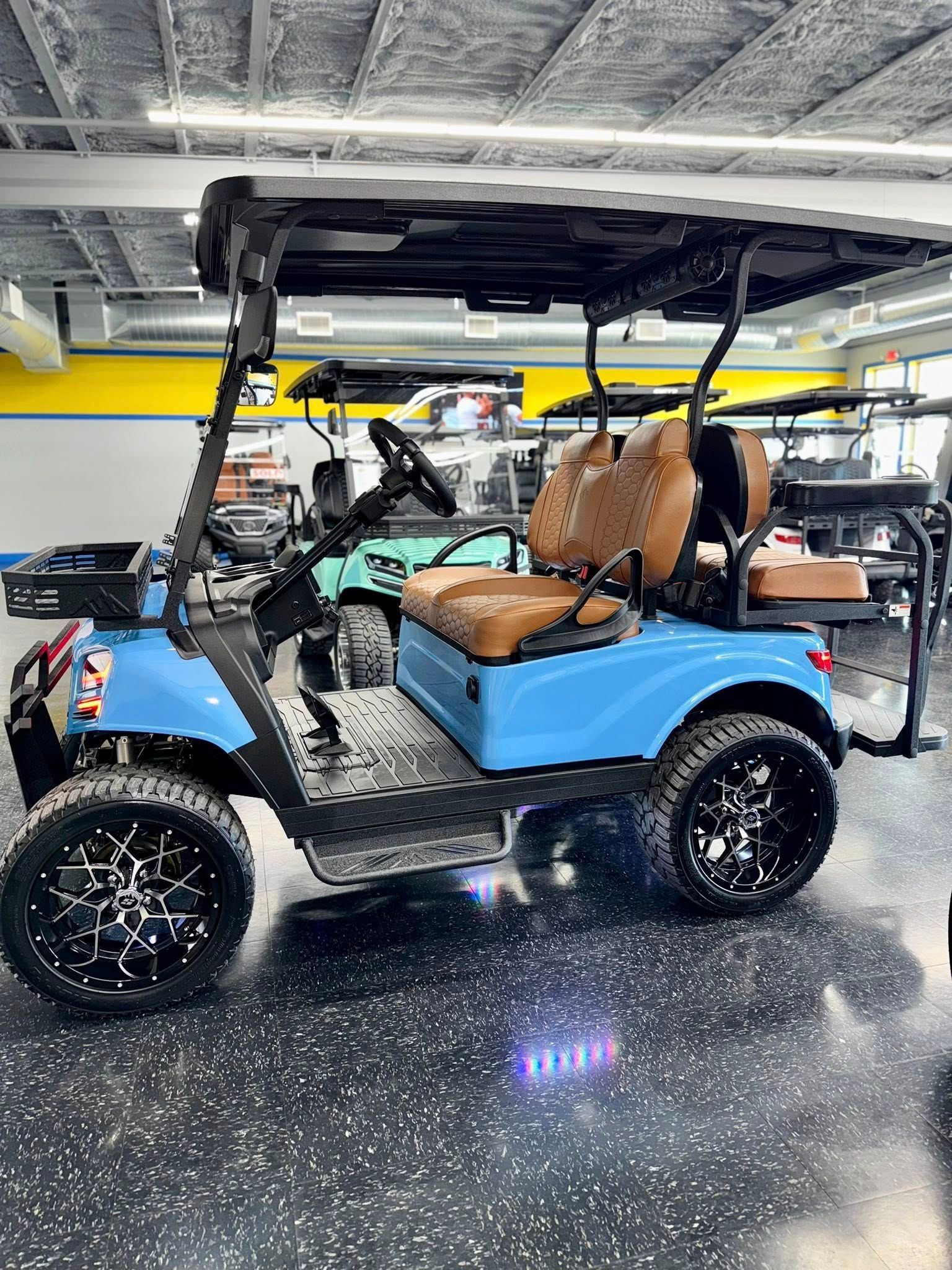 Light blue golf cart with black wheels, roof, and brown seats. In a showroom.
