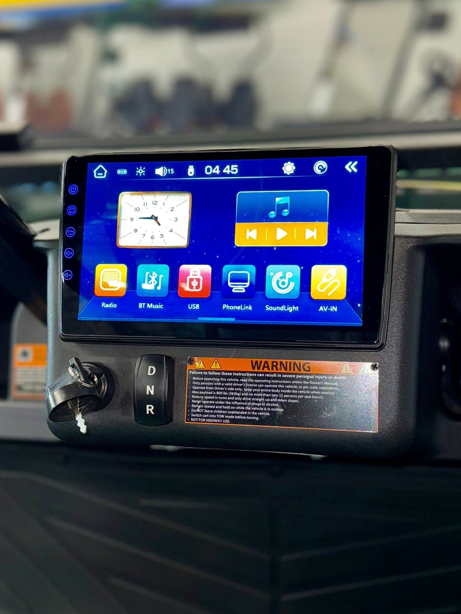Dashboard with touchscreen displaying icons; clock, music, radio. Silver console with key.