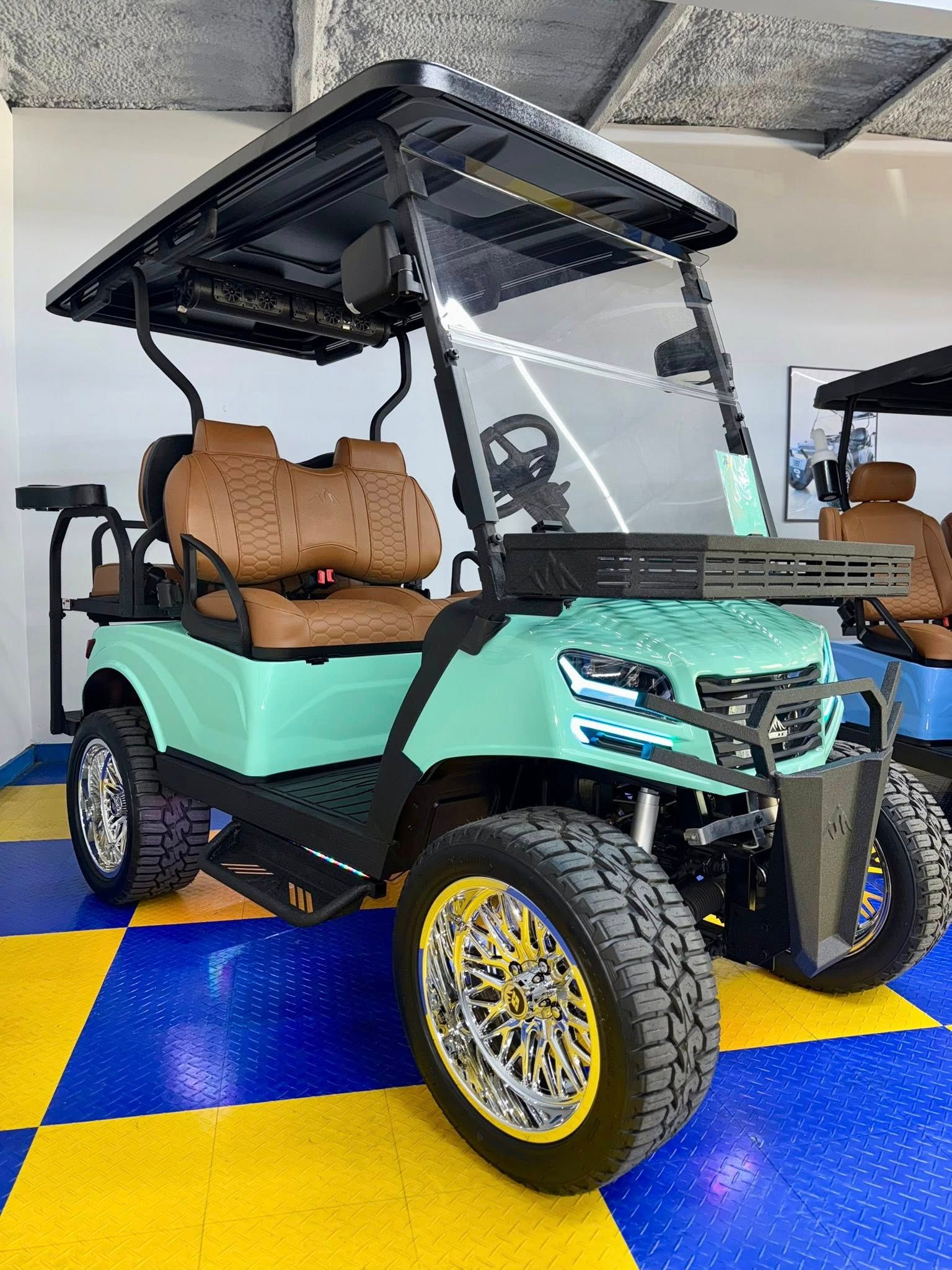 Mint green golf cart with brown seats and chrome wheels.
