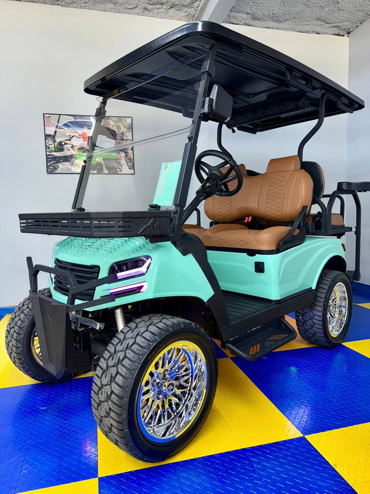 Teal golf cart with black accents, lifted, custom wheels, and brown seats.