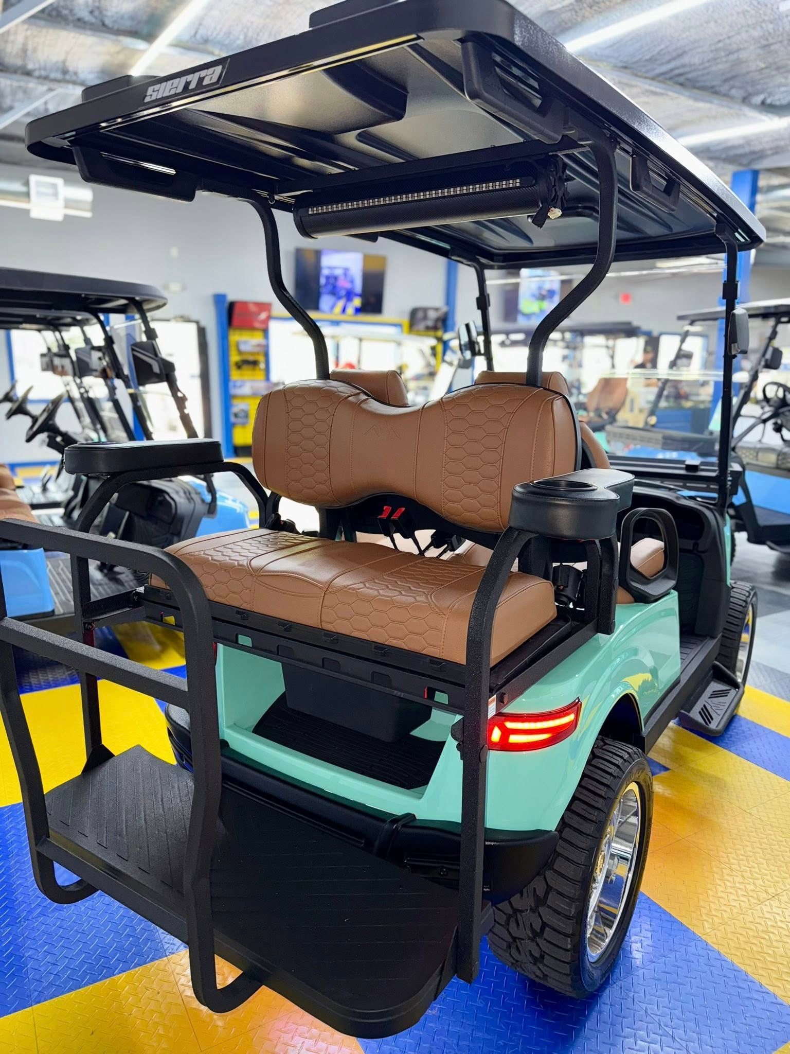 Teal golf cart with brown seats and black roof in a showroom.