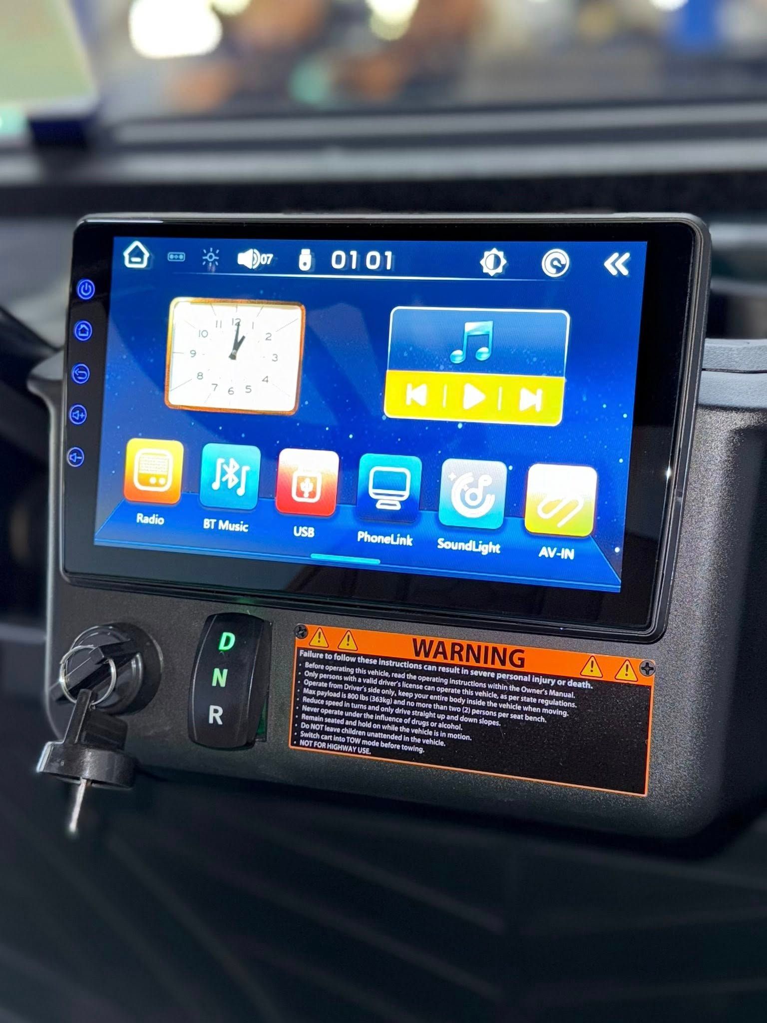Dashboard with touchscreen, buttons, and a warning label. Blue screen displays icons.