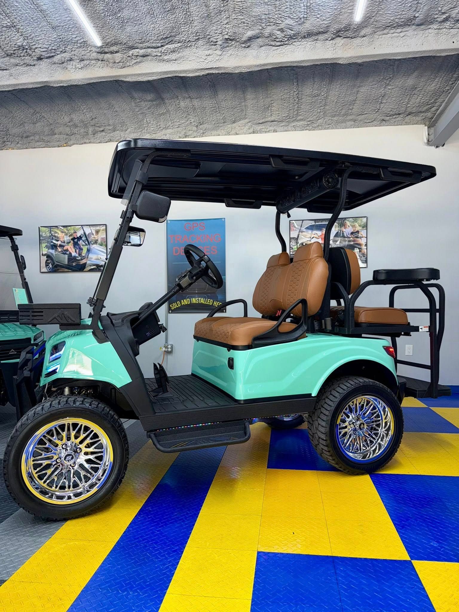 Mint green golf cart with brown seats, black roof and gold and silver wheels.