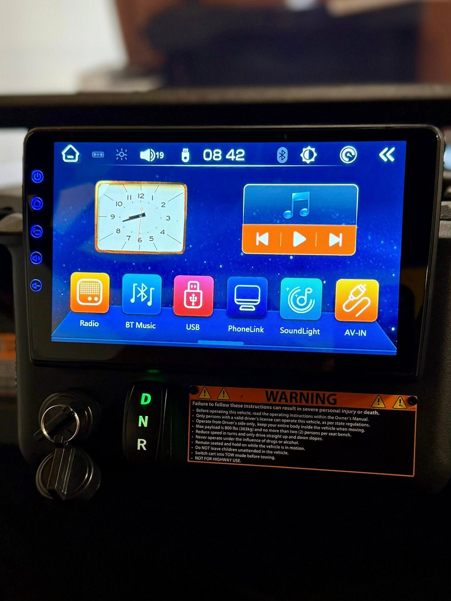 Car dashboard with digital display showing icons, music controls, and time.