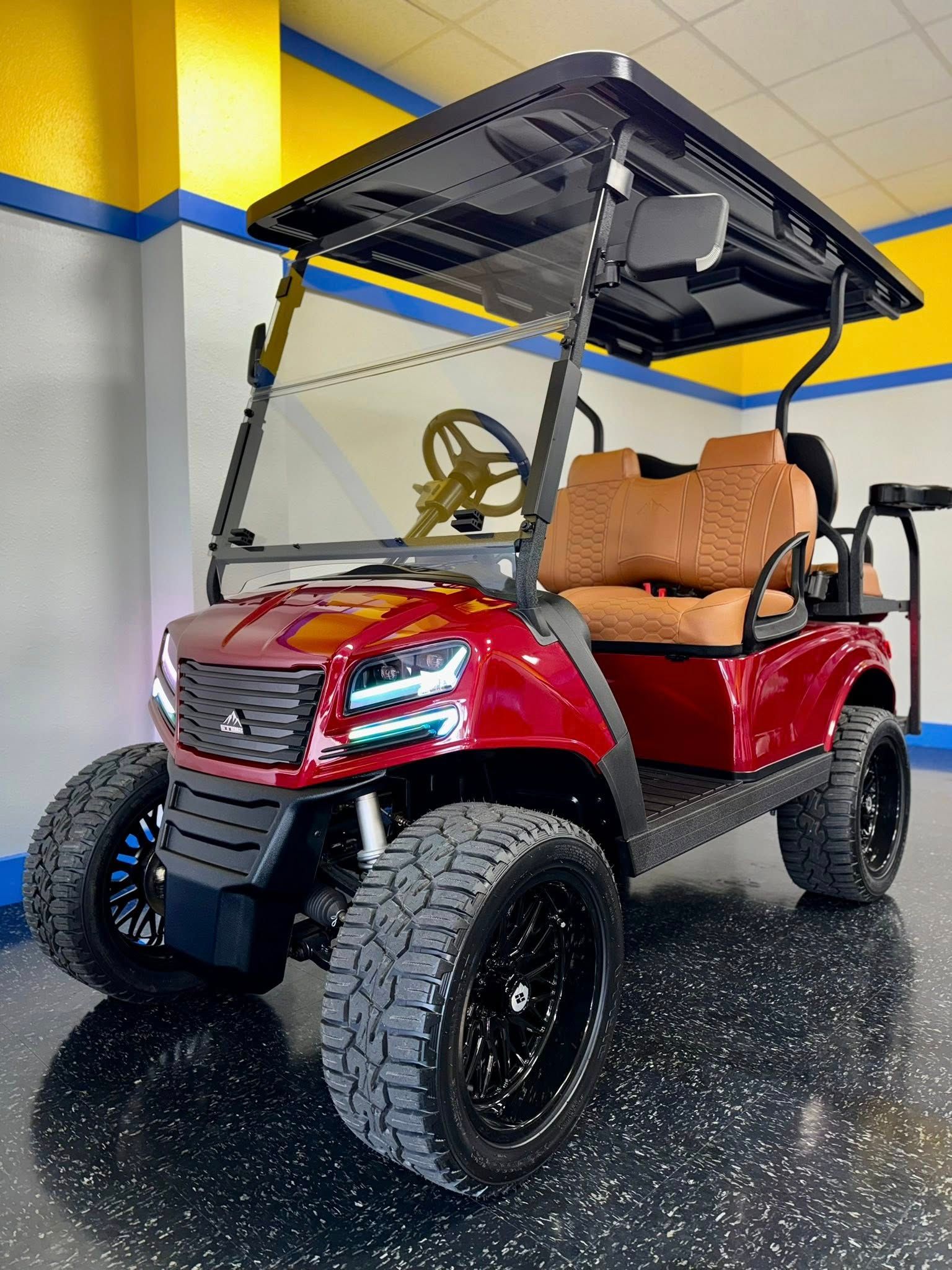 Red golf cart with black wheels, brown seats, and a black roof, indoors.