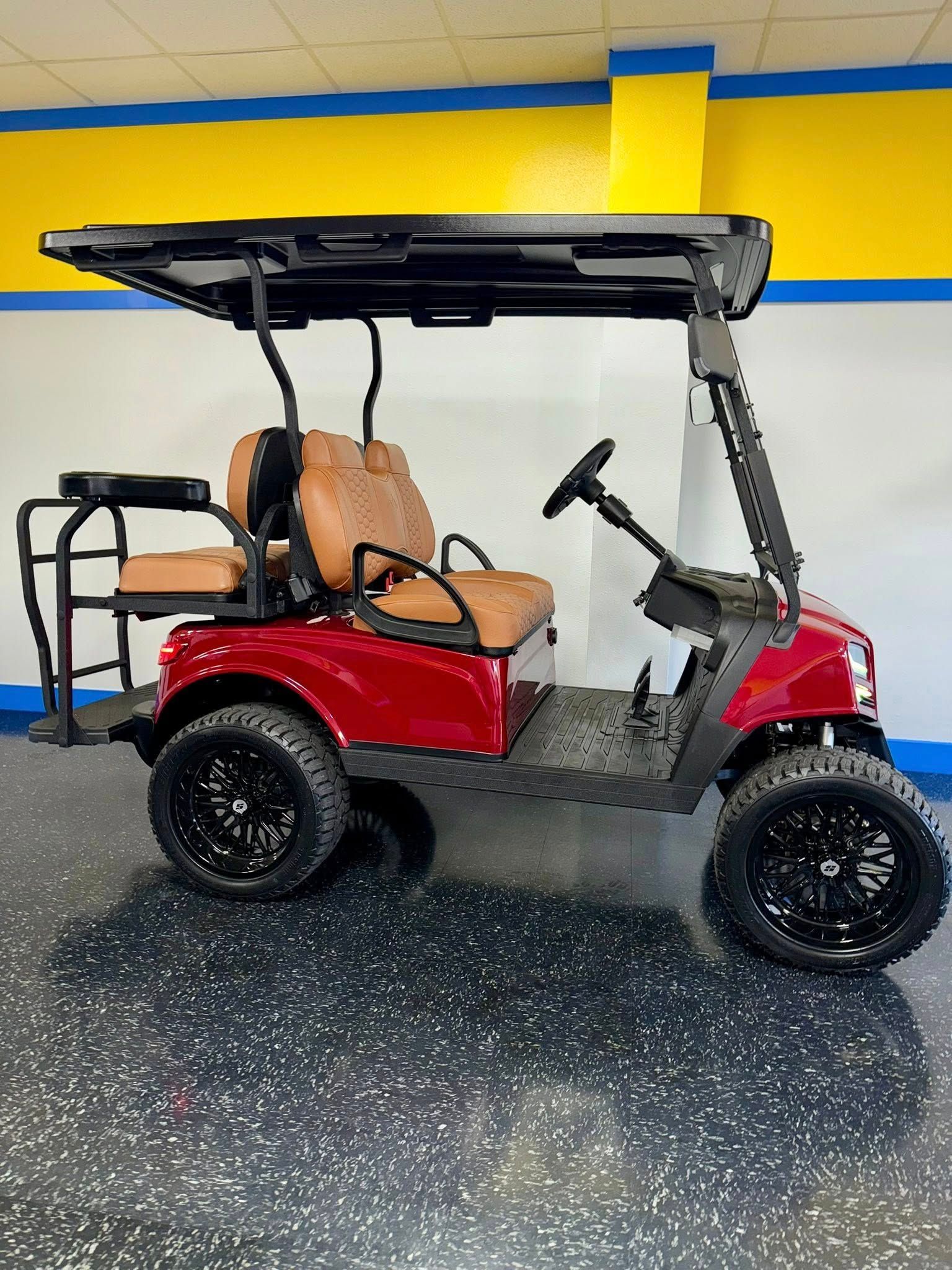 Red golf cart with black wheels, brown seats, and a black roof.