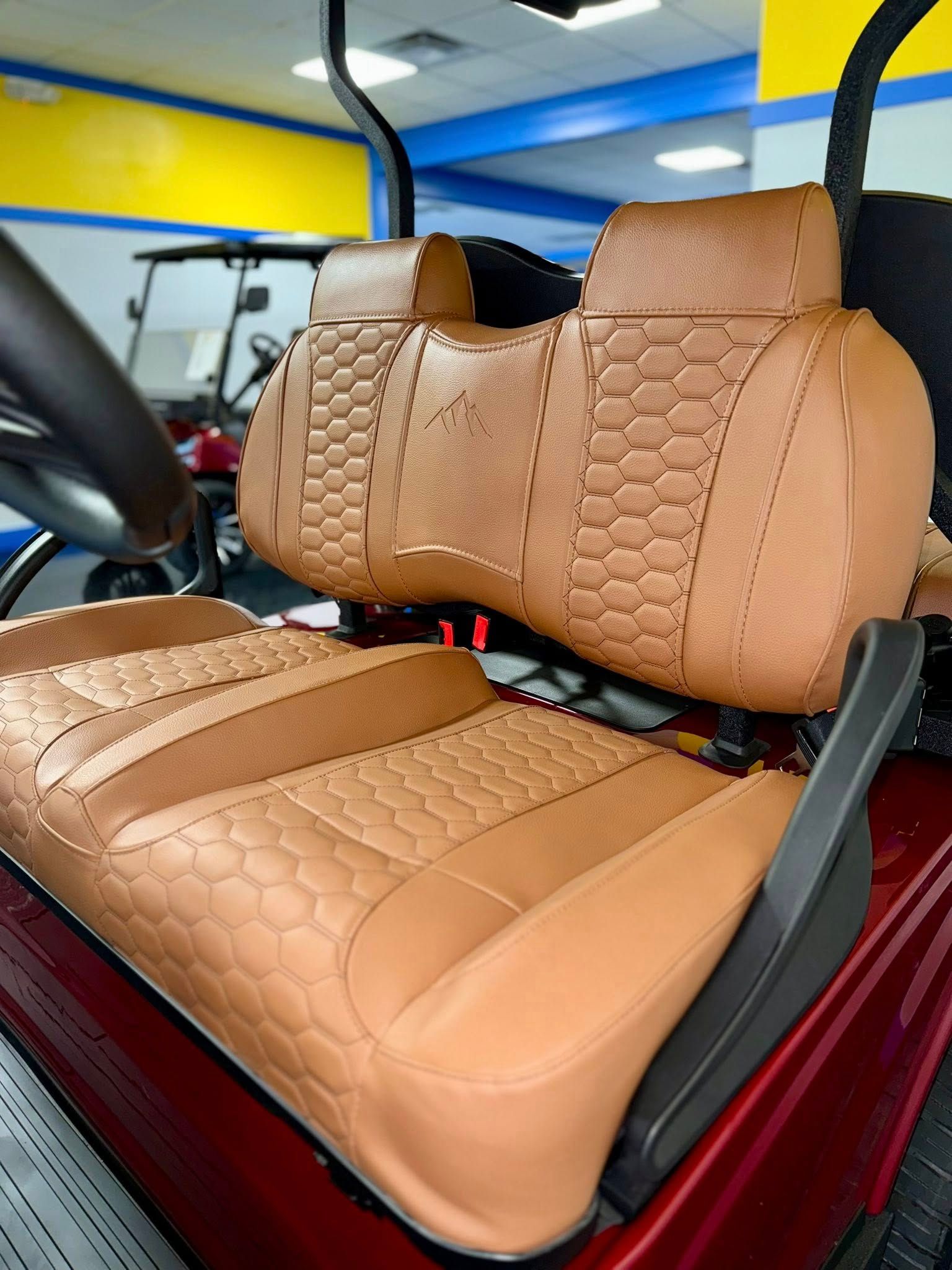 Tan leather golf cart seats with honeycomb pattern, inside a showroom.
