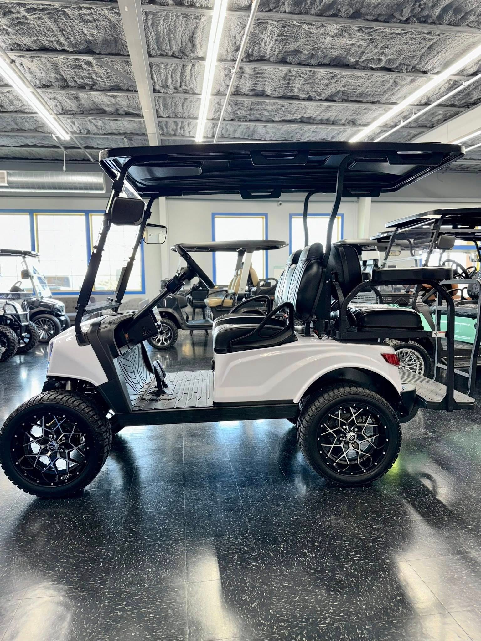 White golf cart with black wheels and canopy in a showroom.