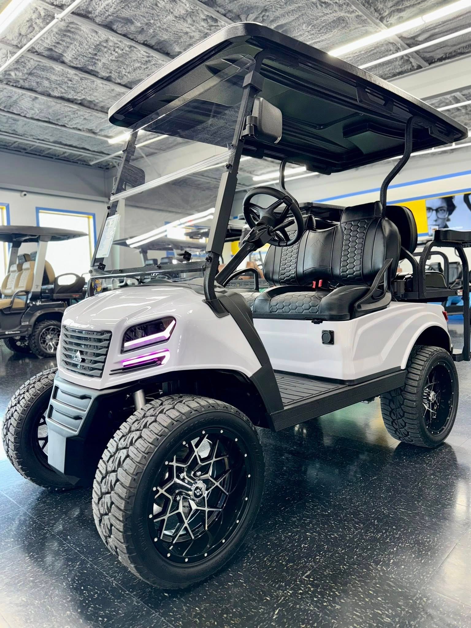 White custom golf cart with black wheels and roof, indoors.