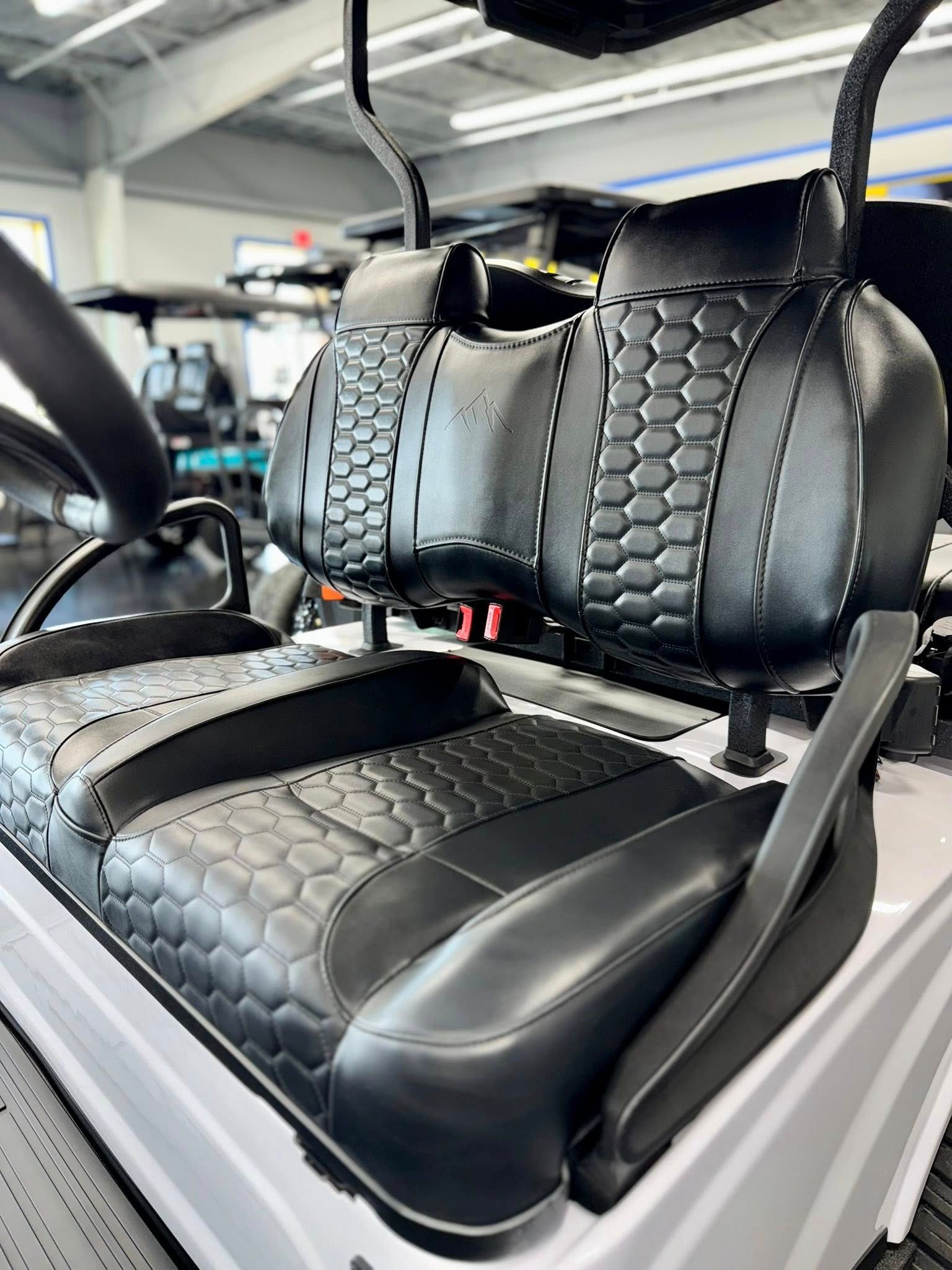 Black and white golf cart interior with textured seats and headrests, in a bright showroom.