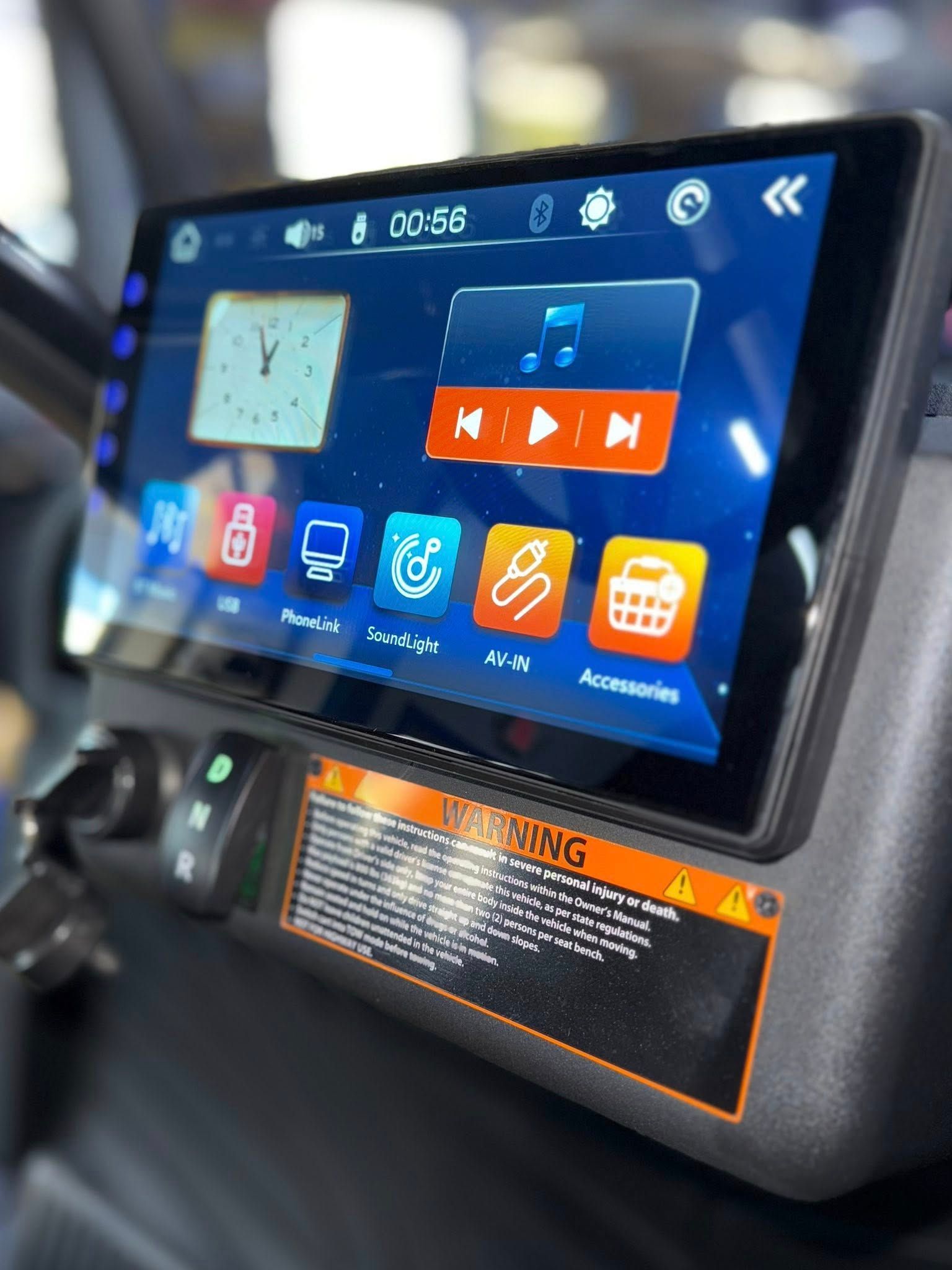 Touchscreen display in vehicle, showing clock, music player, and app icons.