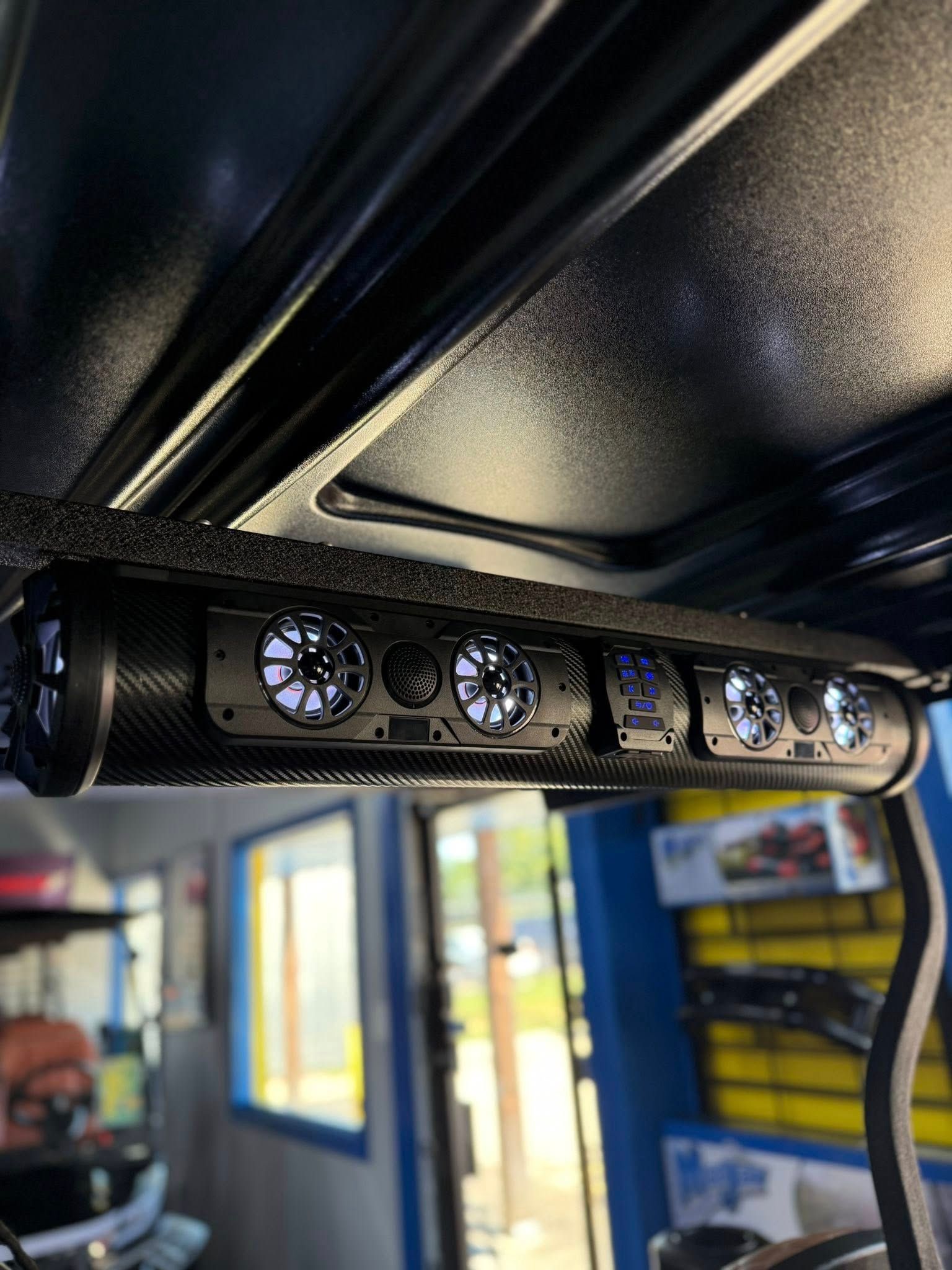A black golf cart soundbar with lit speakers mounted on the roof.