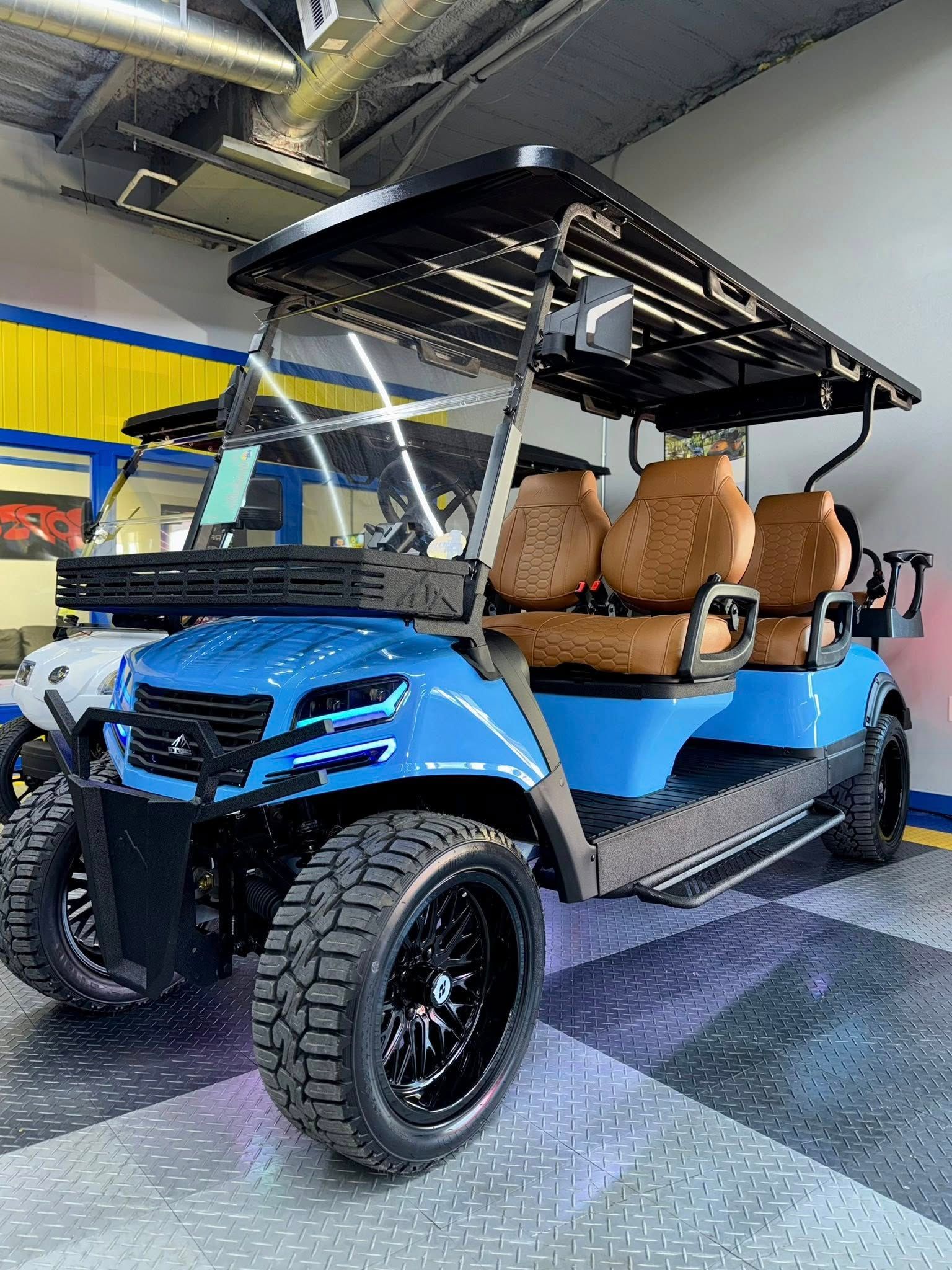 Blue golf cart with black accents and brown seats parked indoors.