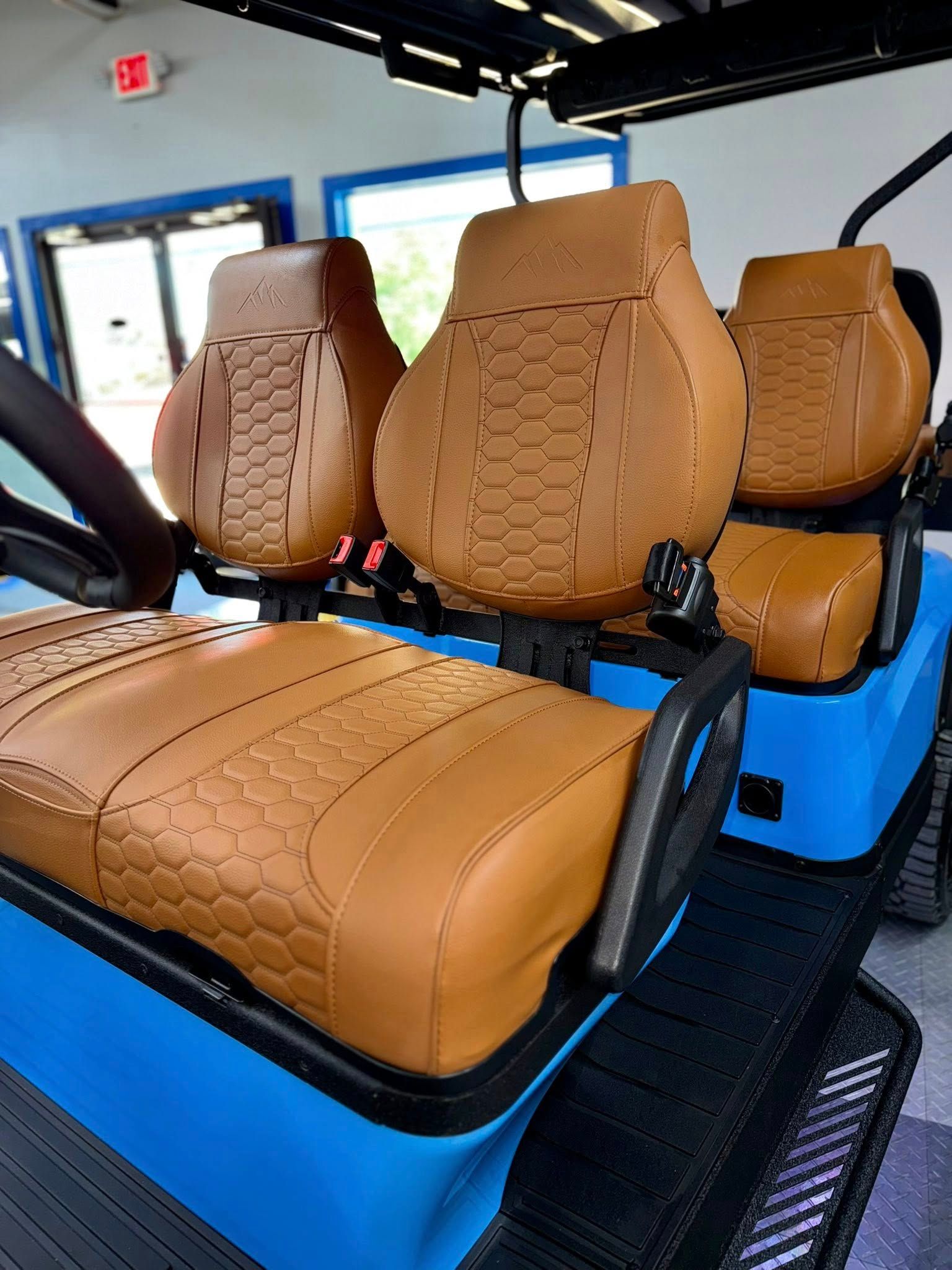 Tan leather seats in a blue golf cart, with a black and blue trim.