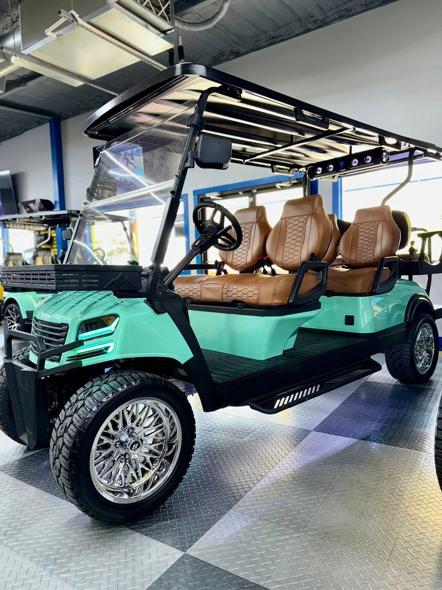 Turquoise golf cart with brown seats, black accents, and chrome wheels, parked indoors.