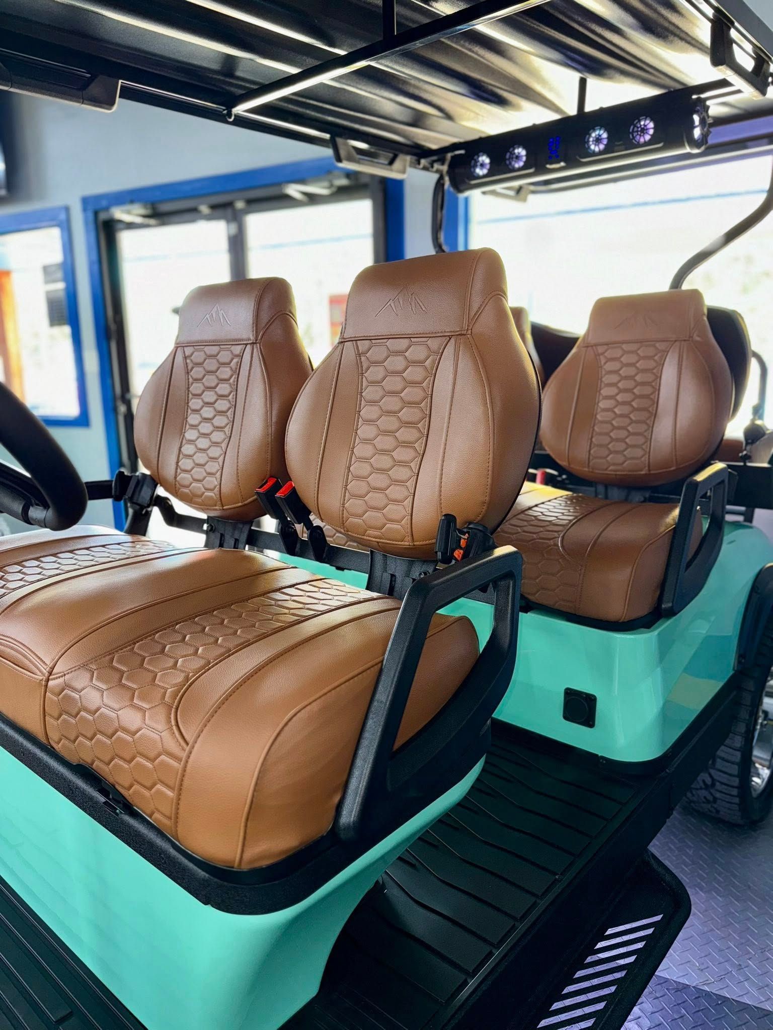 Teal golf cart with brown leather seats.