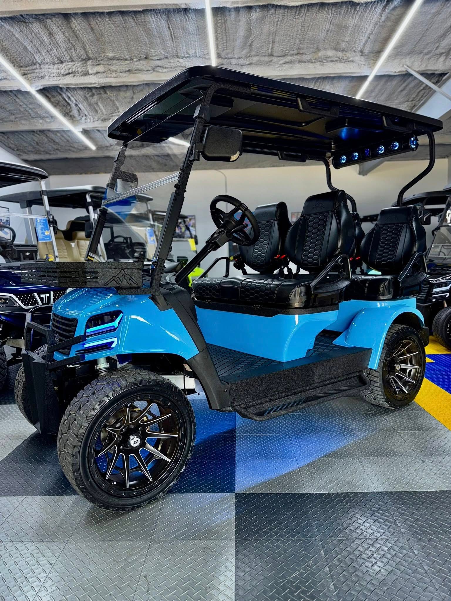 Blue custom golf cart with black accents and large wheels, indoors.